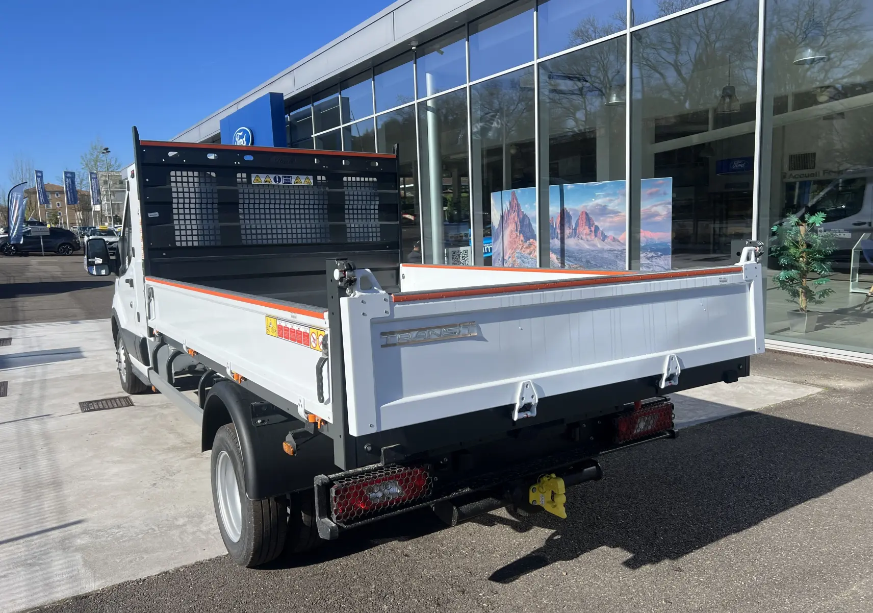 Vue 3/4 arrière droite du Ford Transit Chassis Cabine blanc avec benne et coffre, roues jumelées et attelage visible.
