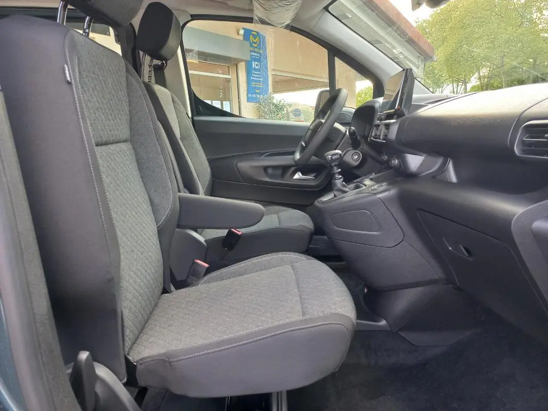 Vue intérieure côté conducteur de l’Opel Combo Life M 2025, sièges gris avec accoudoir et tableau de bord noir.