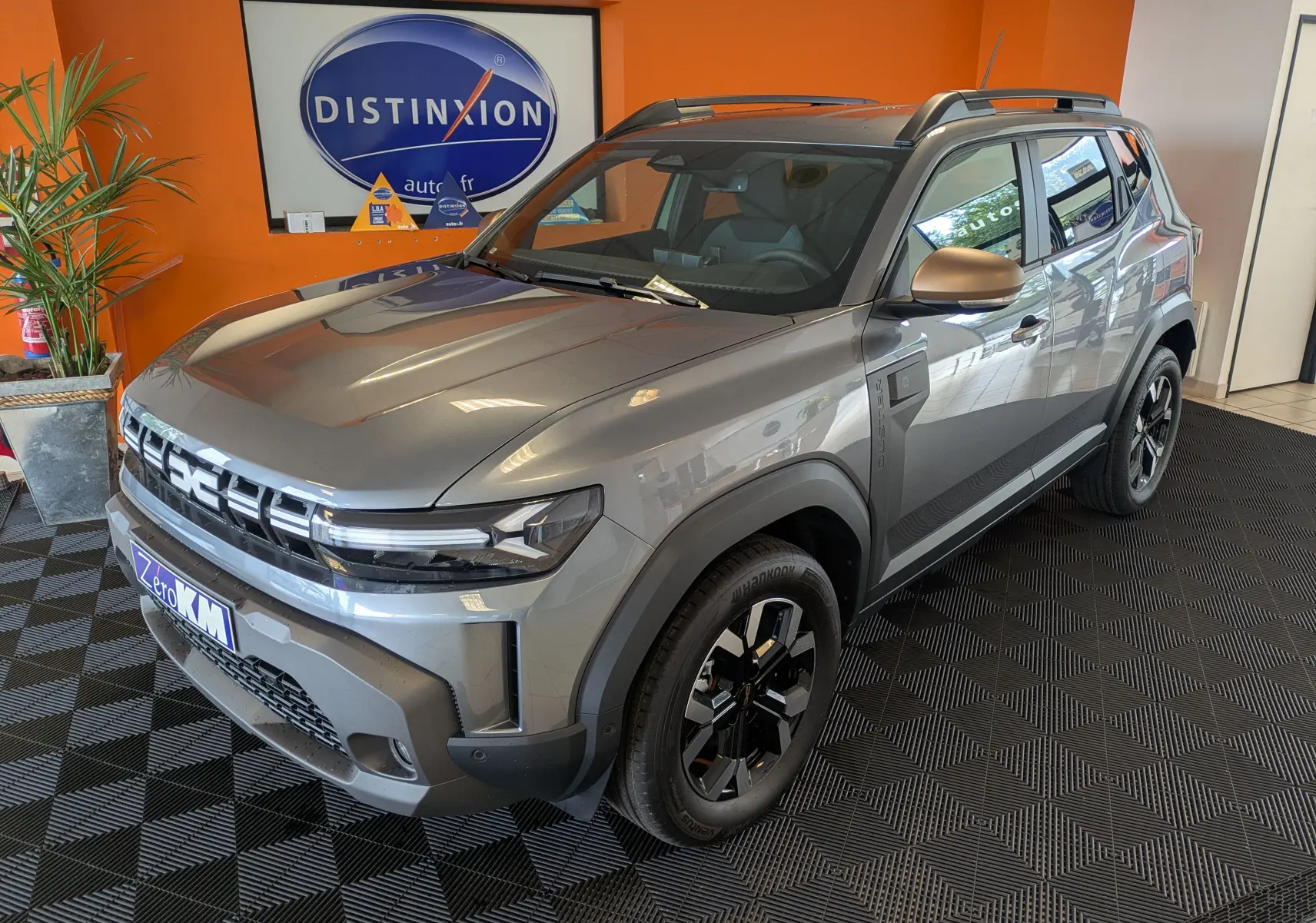 Vue 3/4 avant droit du Dacia Duster 1.6 Hybrid 140 Extreme gris schiste avec jantes biton et barres de toit.