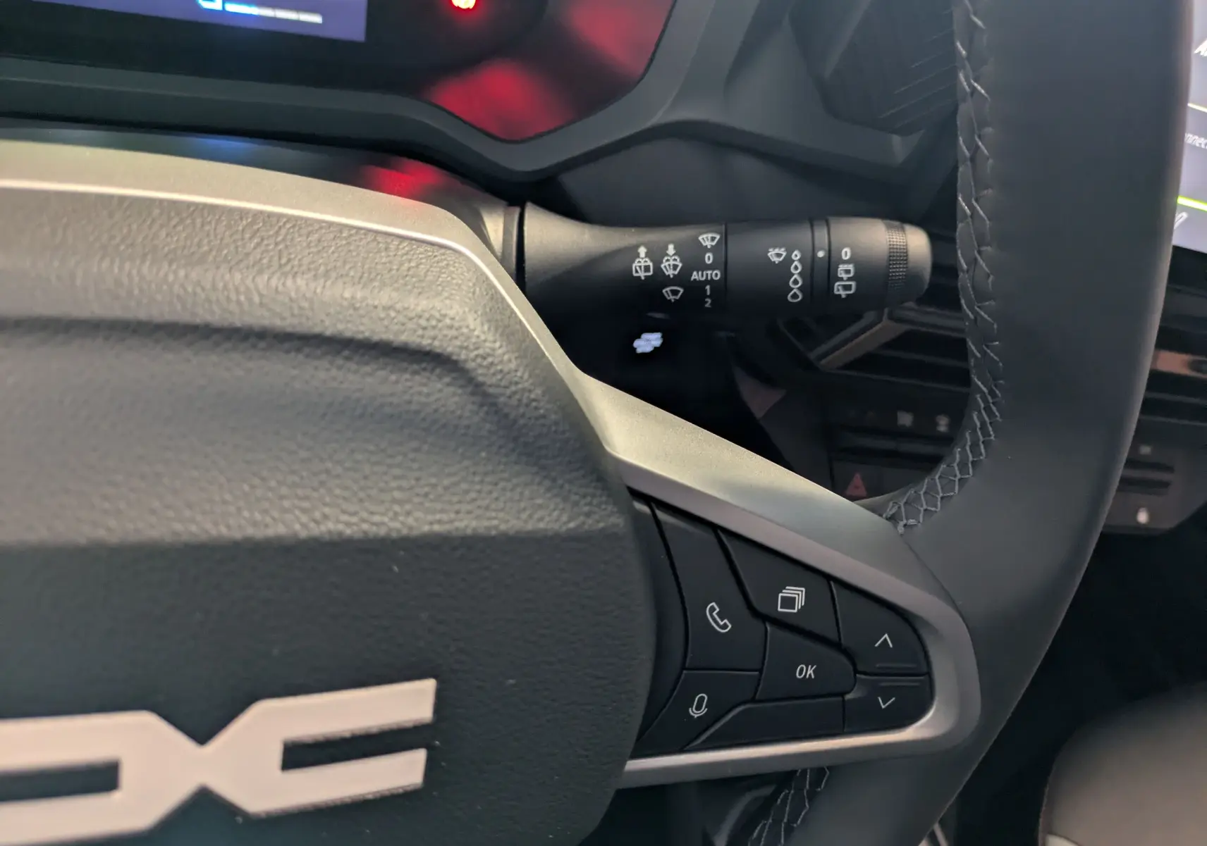 Gros plan sur le volant du Dacia Duster 1.6 Hybrid 140 Extreme 2025, avec commandes intégrées et surpiqûres visibles.