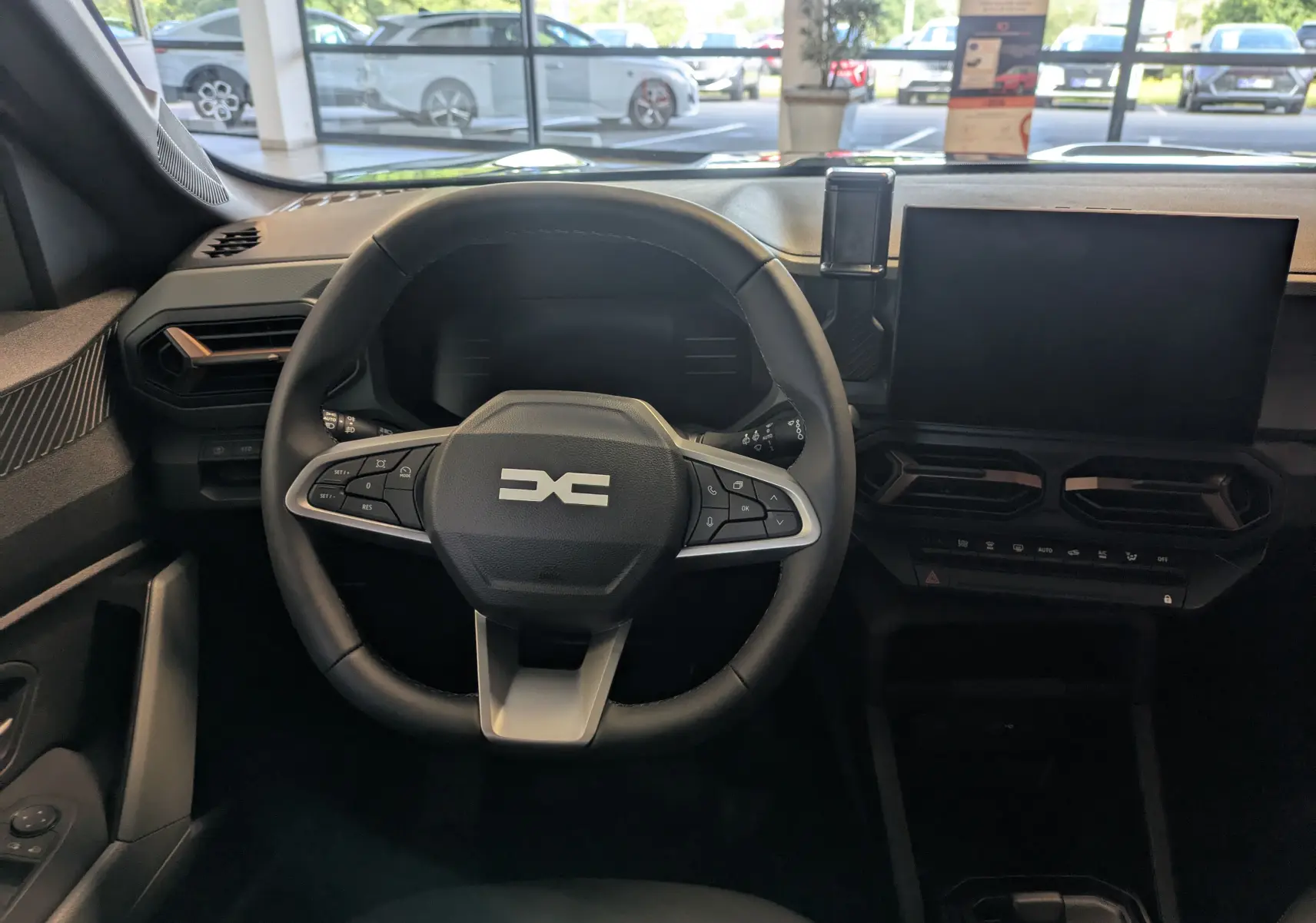Vue intérieure du tableau de bord du Dacia Duster 1.6 Hybrid 140 Extreme 2025 avec volant multifonction et écran tactile.