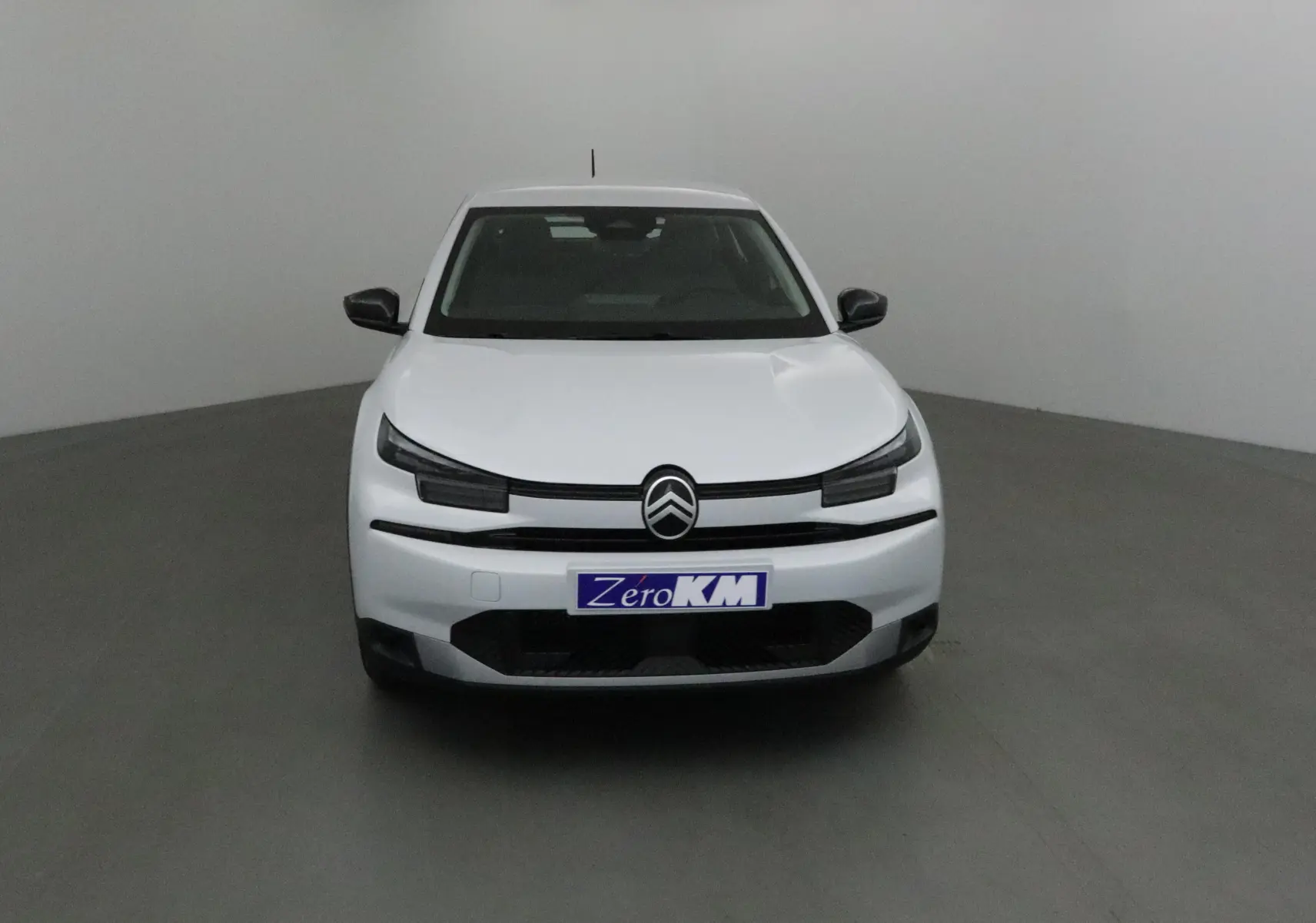 Vue frontale d'une Citroën C4 1.2 Hybrid 136 blanc Okenite avec calandre noire et logo centré.