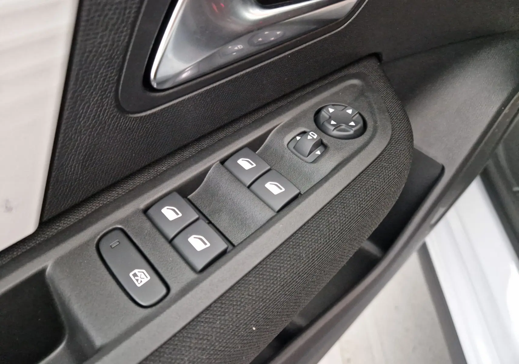 Gros plan sur les commandes de lève-vitres et rétroviseurs côté conducteur d'une Citroën C4 blanche 2025.