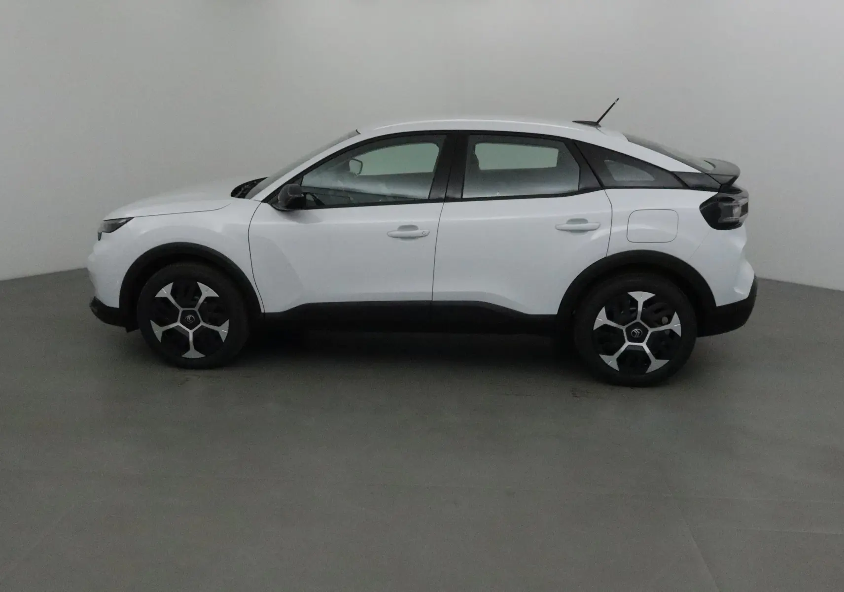 Profil côté gauche d'une Citroën C4 blanc Okenite 2025 avec jantes noires et détails noirs contrastants.