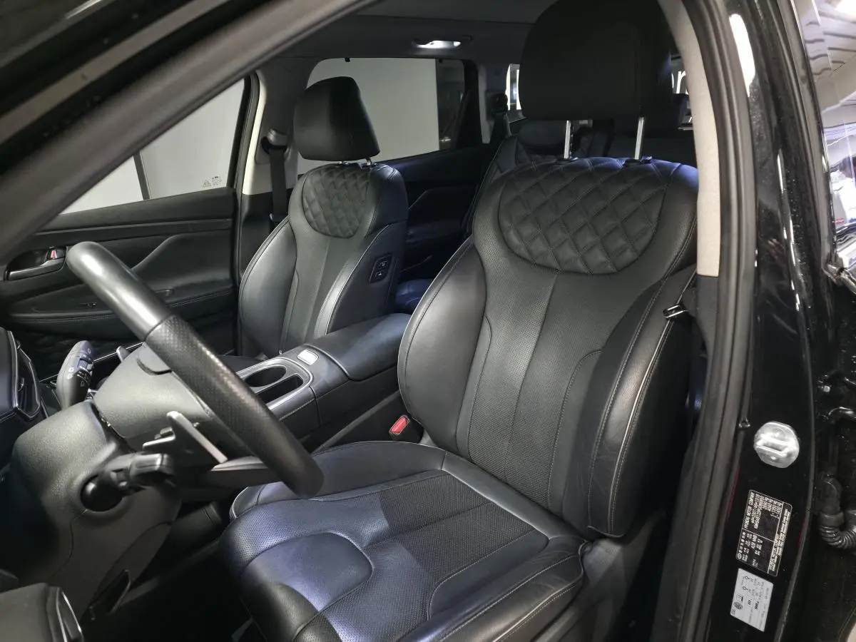 Vue intérieure côté conducteur du Hyundai Santa Fé 2023 noir, sièges cuir noir matelassé et volant cuir perforé.