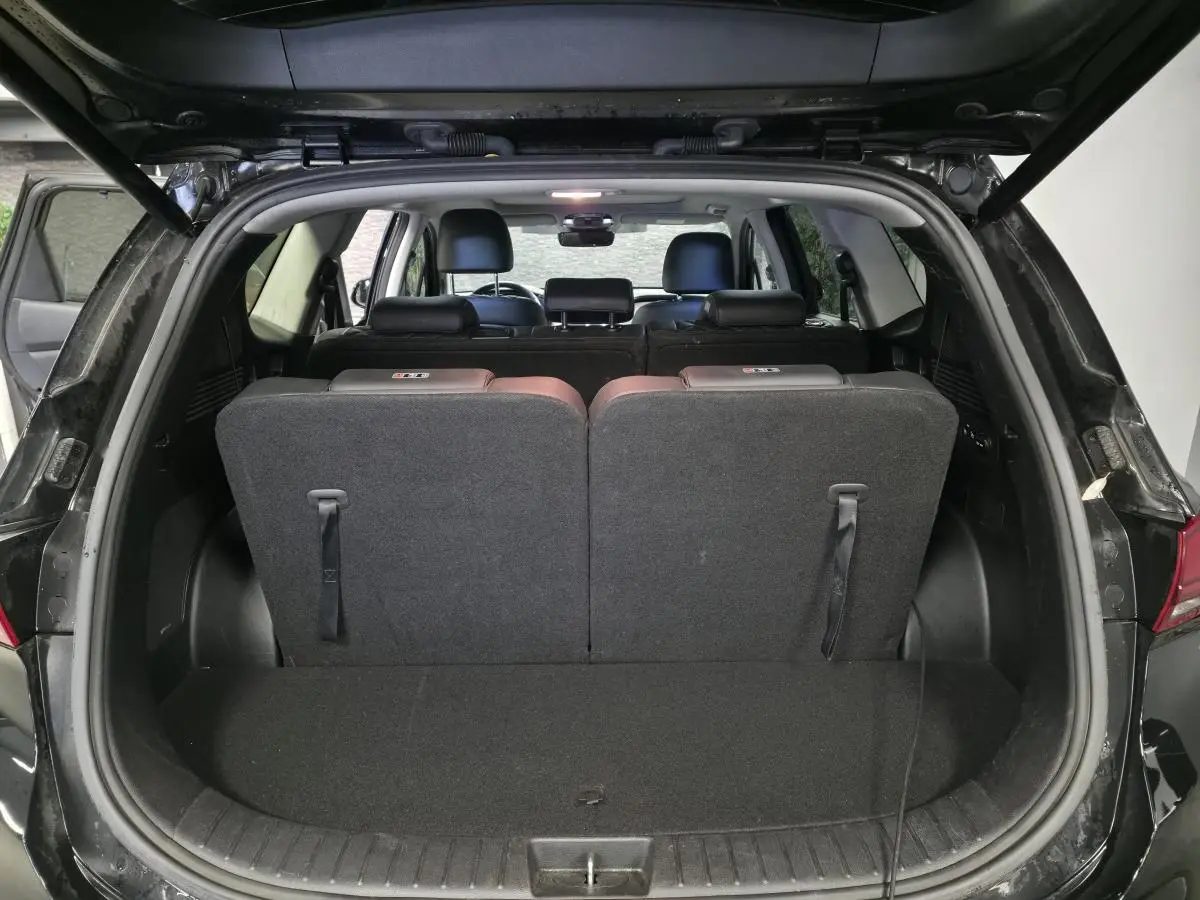 Vue arrière du coffre ouvert du Hyundai Santa Fé noir 2023, montrant la troisième rangée de sièges relevée.