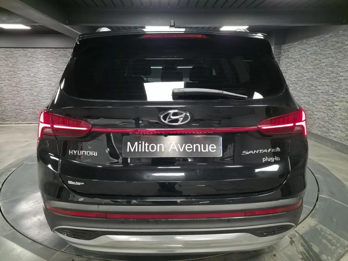 Vue arrière d'un Hyundai Santa Fé noir hybride rechargeable avec feux LED et logo distinctif dans un garage.