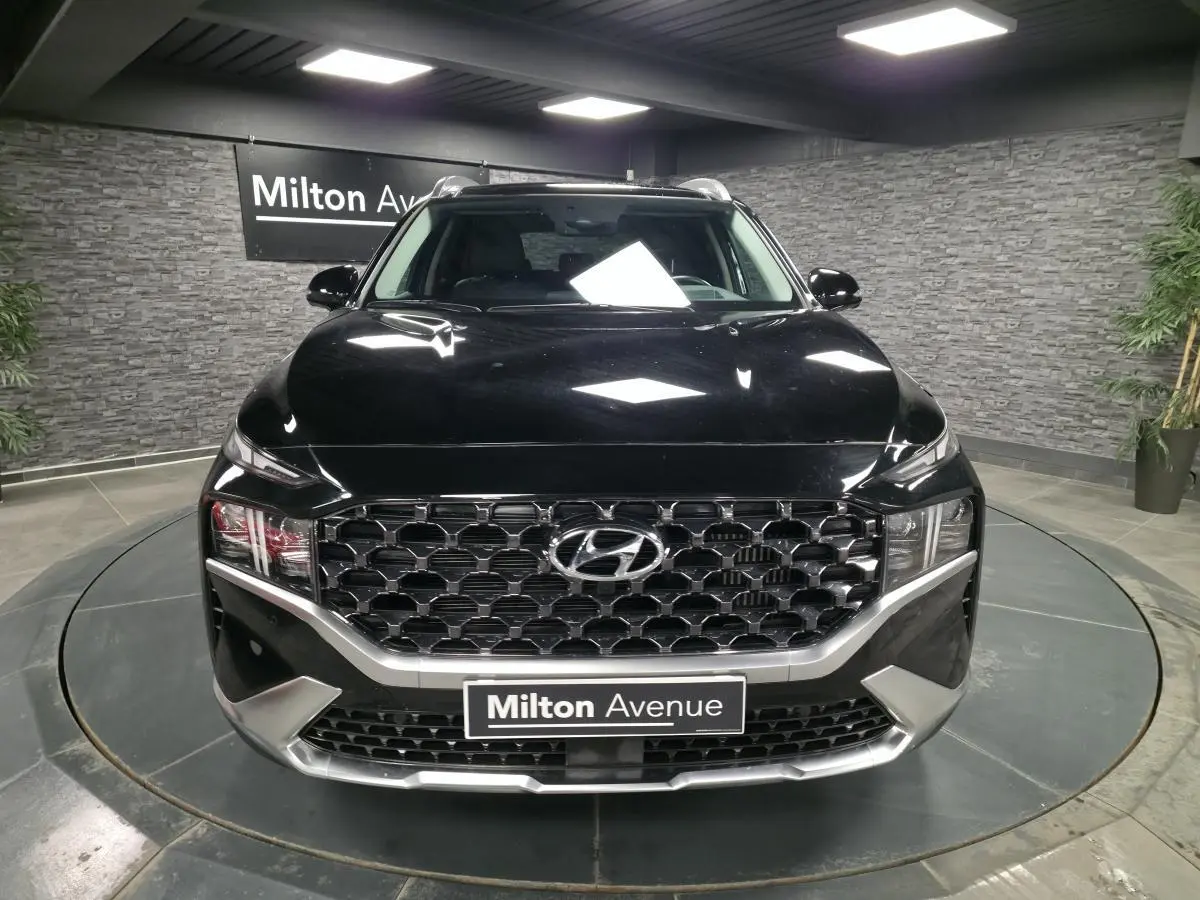 Vue frontale d'un Hyundai Santa Fé noir avec calandre hexagonale chromée et éclairage LED dans un showroom.
