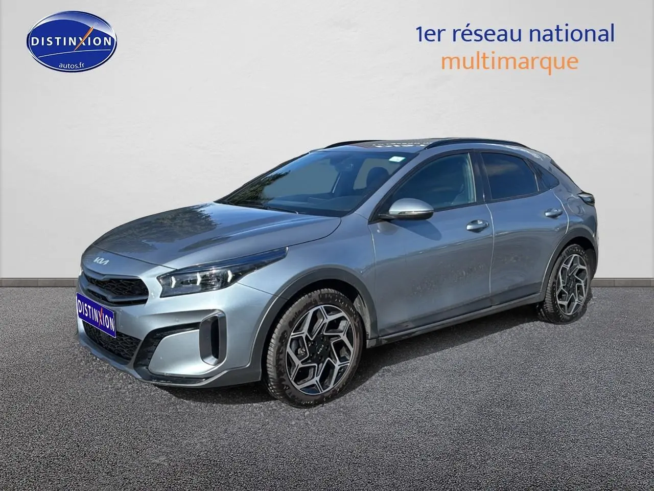 KIA Xceed gris en 3/4 avant droit, avec jantes alu au design hexagonal et calandre chromée visible.