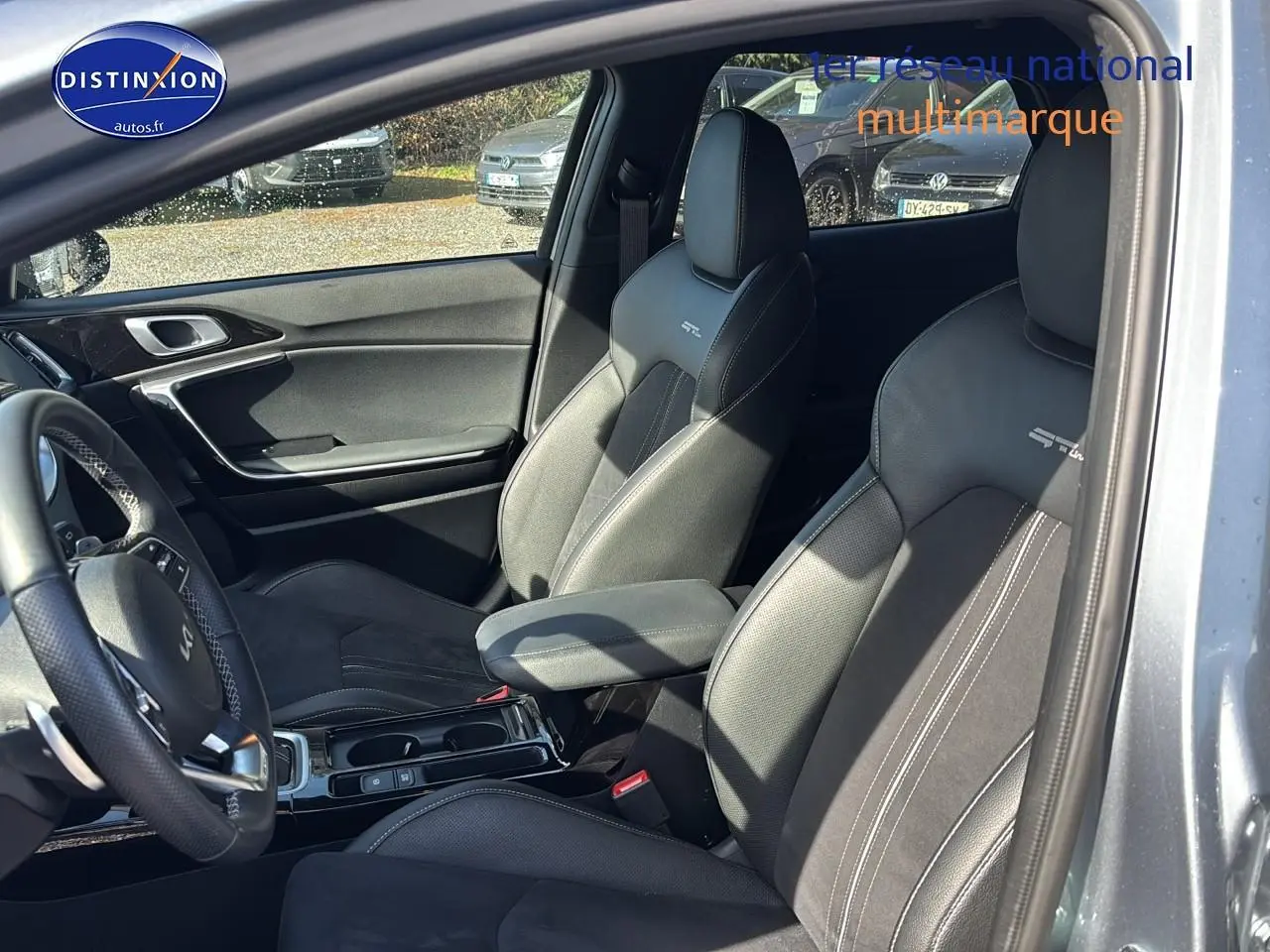 Vue intérieure côté conducteur du Kia Xceed gris 2024, sièges sport GT-Line avec surpiqûres blanches et accoudoir central.