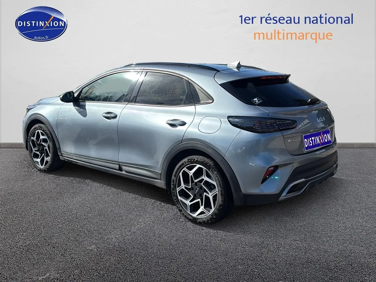 Vue 3/4 arrière droite d'un KIA Xceed gris avec jantes alu et vitres arrière surteintées sur fond neutre.