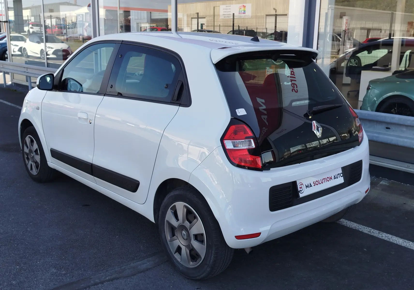 Renault Twingo blanc cristal vue 3/4 arrière droit, avec vitres teintées et jantes spécifiques.