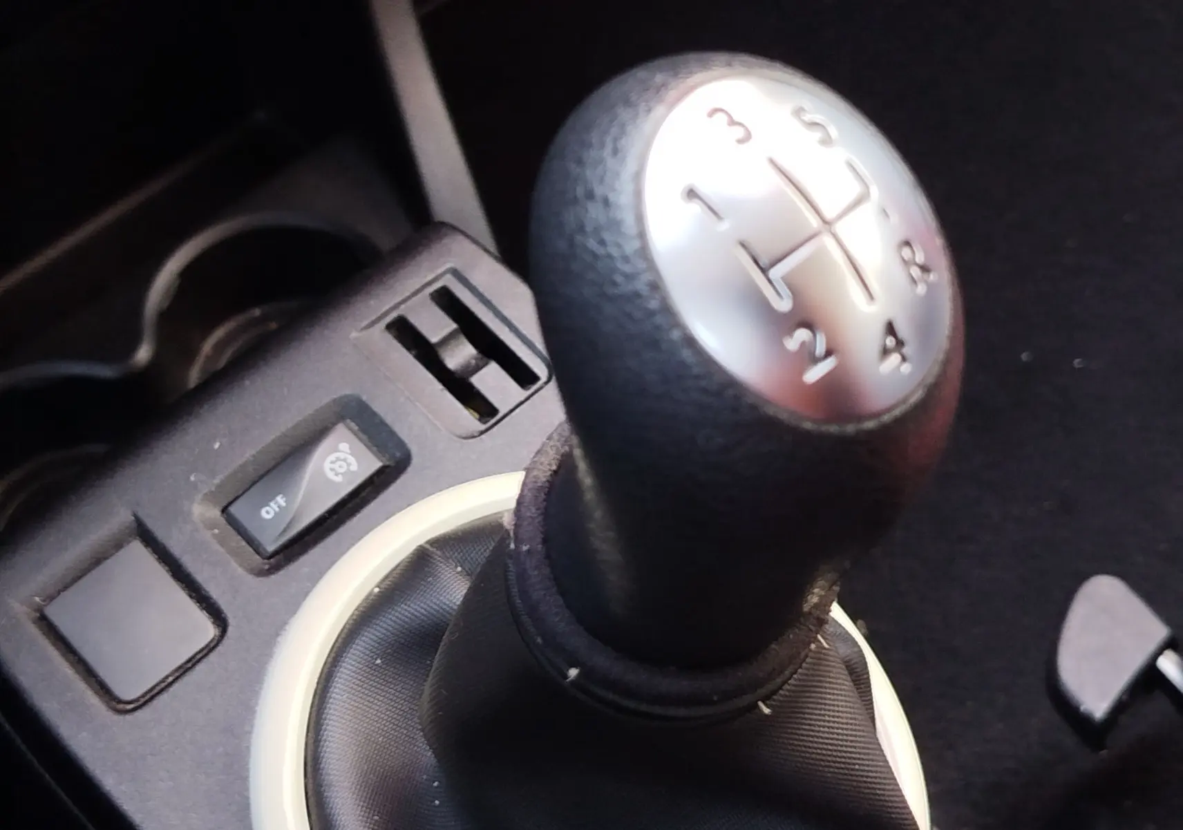 Gros plan sur le levier de vitesses manuel noir avec marquages argentés dans une Renault Twingo Blanc Cristal de 2016.