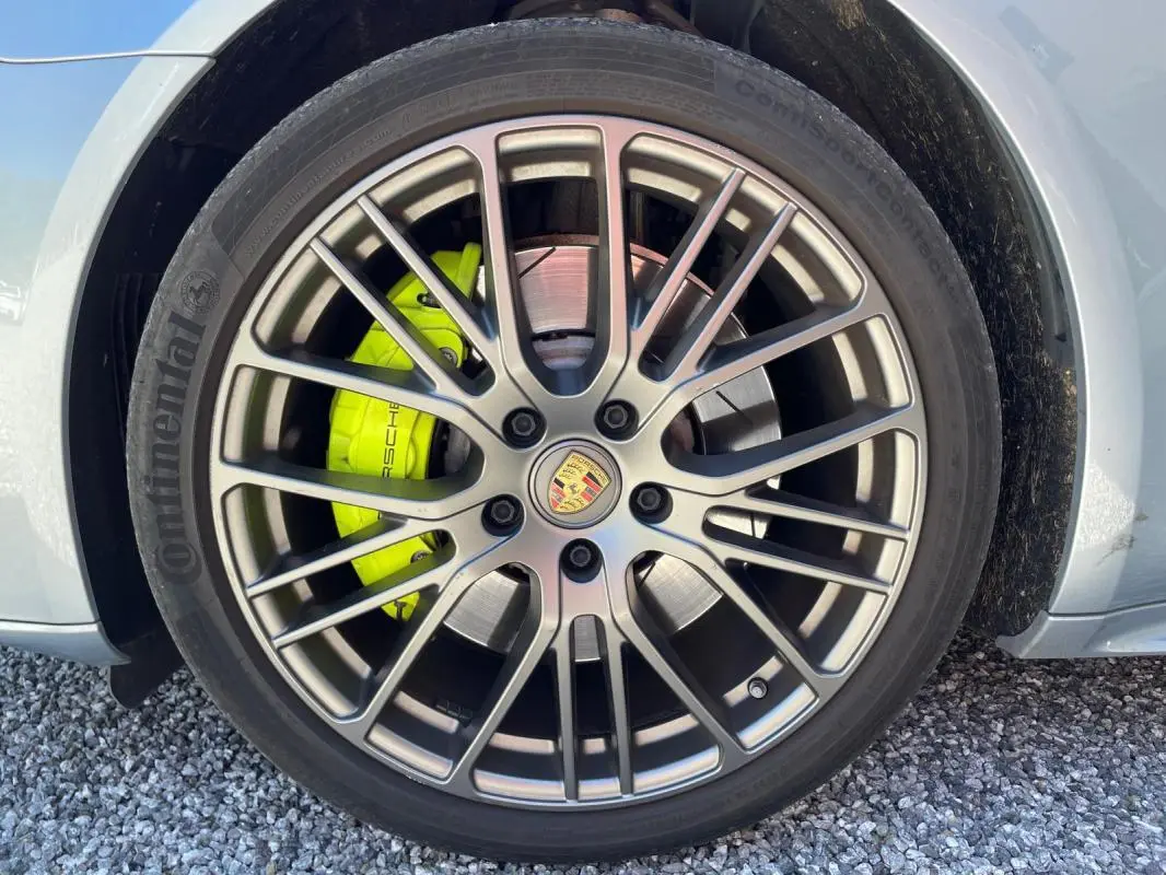 Gros plan sur la roue avant droite grise d'une Porsche Panamera 4 Hybrid avec étrier de frein jaune vif.