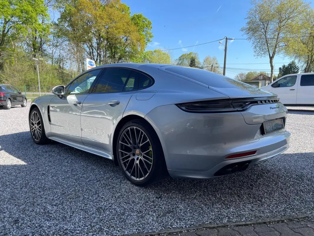 Vue 3/4 arrière droite d'une Porsche Panamera 4 V6 3.0 Hybrid gris métallisé avec jantes noires distinctives.