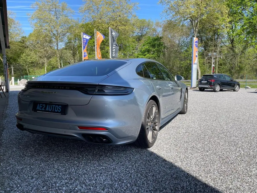 Vue 3/4 arrière droite d'une Porsche Panamera 4 V6 3.0 Hybrid gris métallisé avec feux arrière allongés et jantes sport.