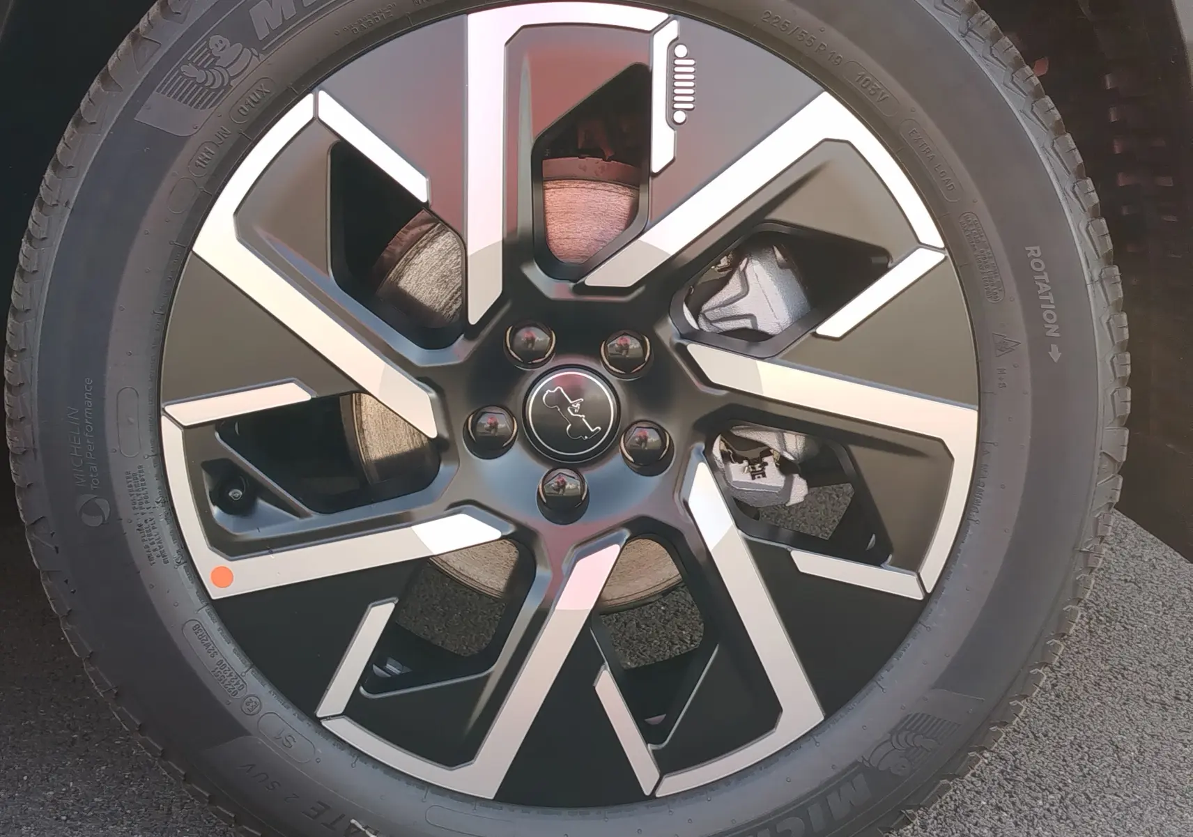 Gros plan sur la jante noire et argentée du Jeep Compass 2026 en Noir Vulcano Metal, mettant en valeur le logo central.