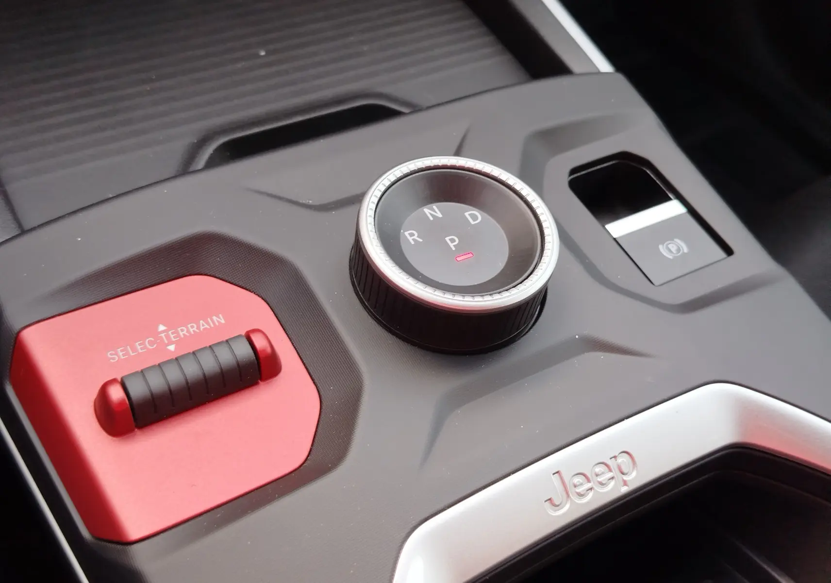 Gros plan sur la console centrale du Jeep Compass noir Vulcano, avec sélecteur de mode terrain rouge et molette de boîte auto.