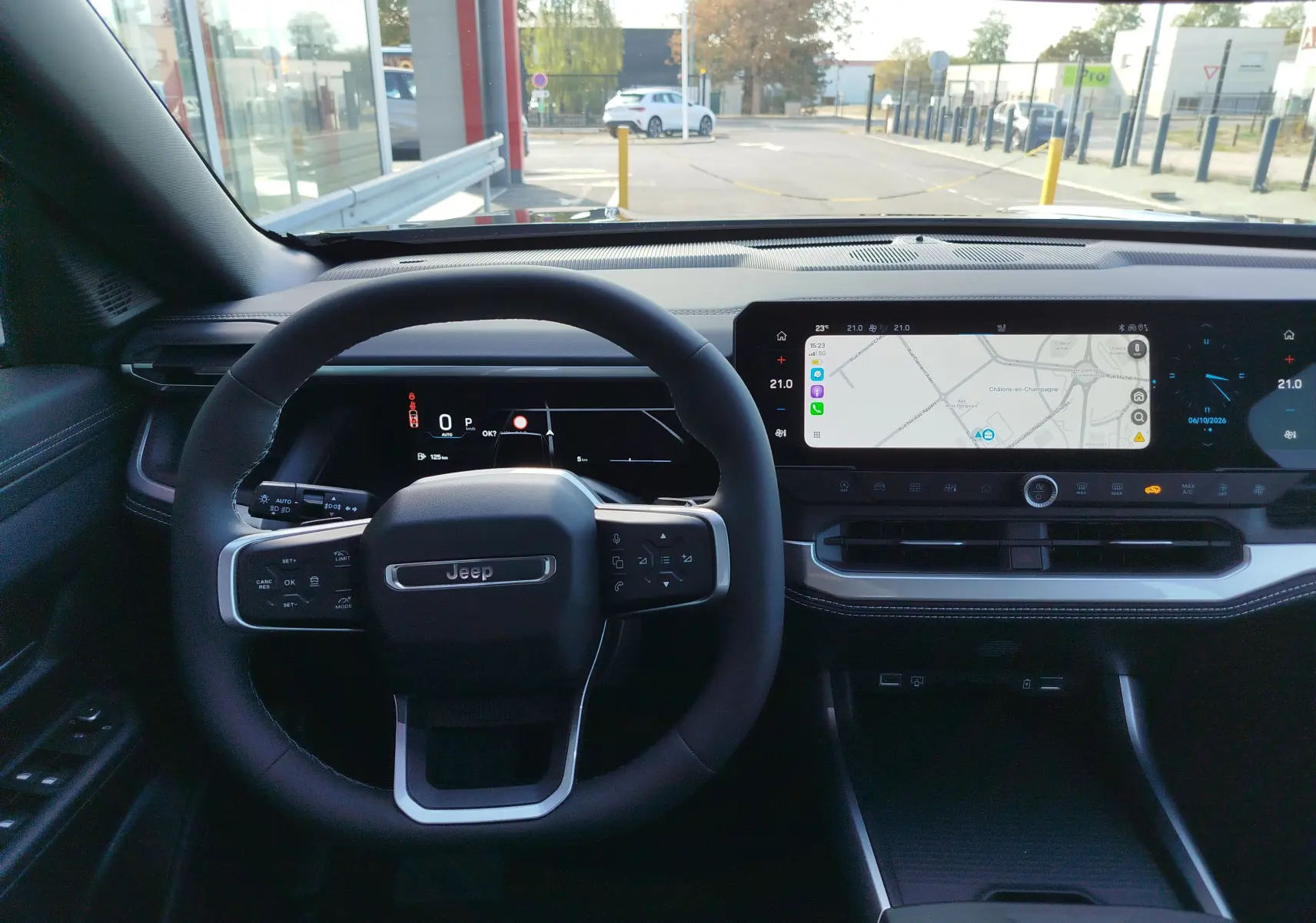 Vue intérieure centrée sur le volant et le tableau de bord numérique du Jeep Compass noir avec écran tactile de navigation.