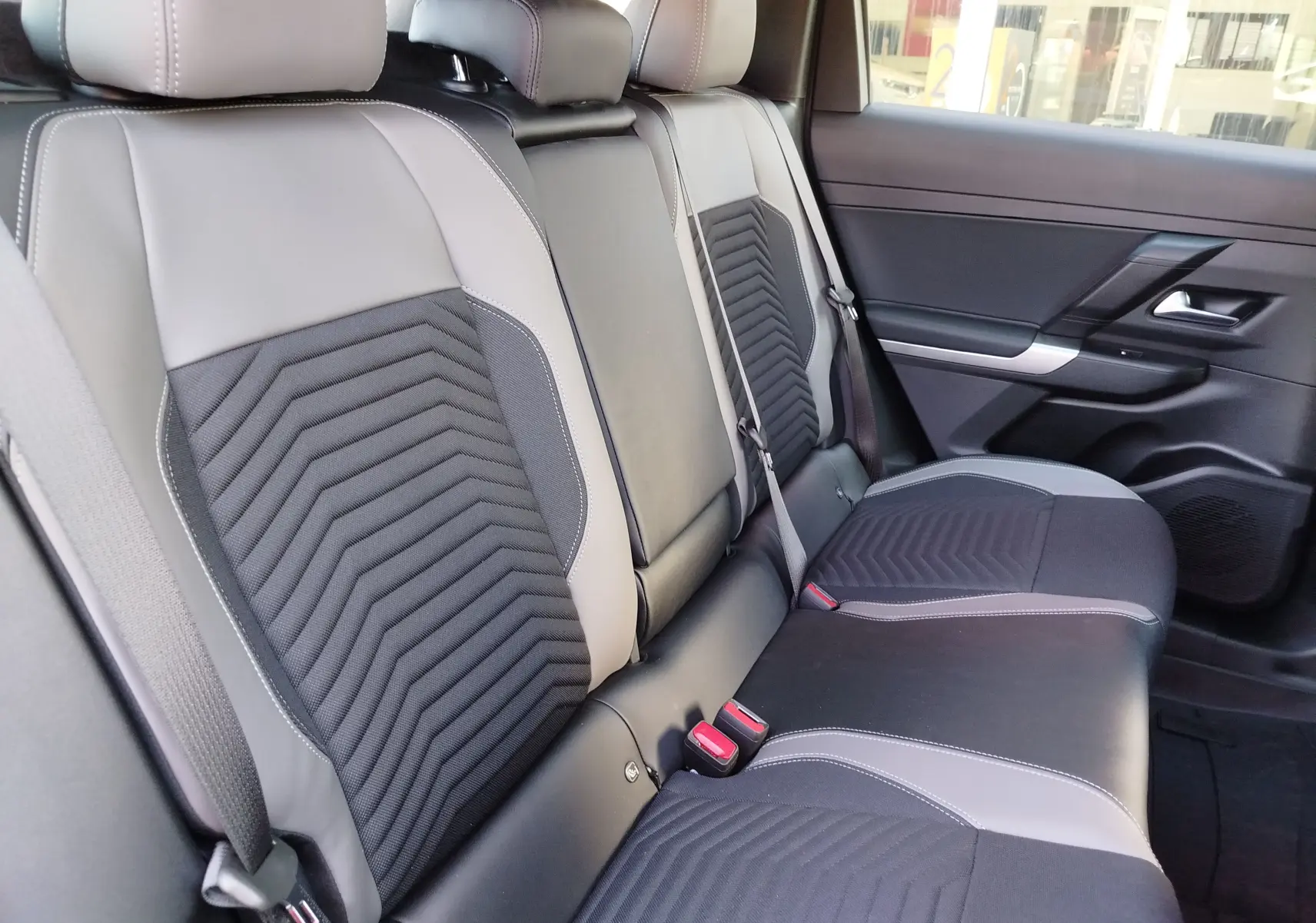 Vue intérieure des sièges arrière du Jeep Compass 2026, avec sellerie bicolore noire et grise et détails en tissu texturé.