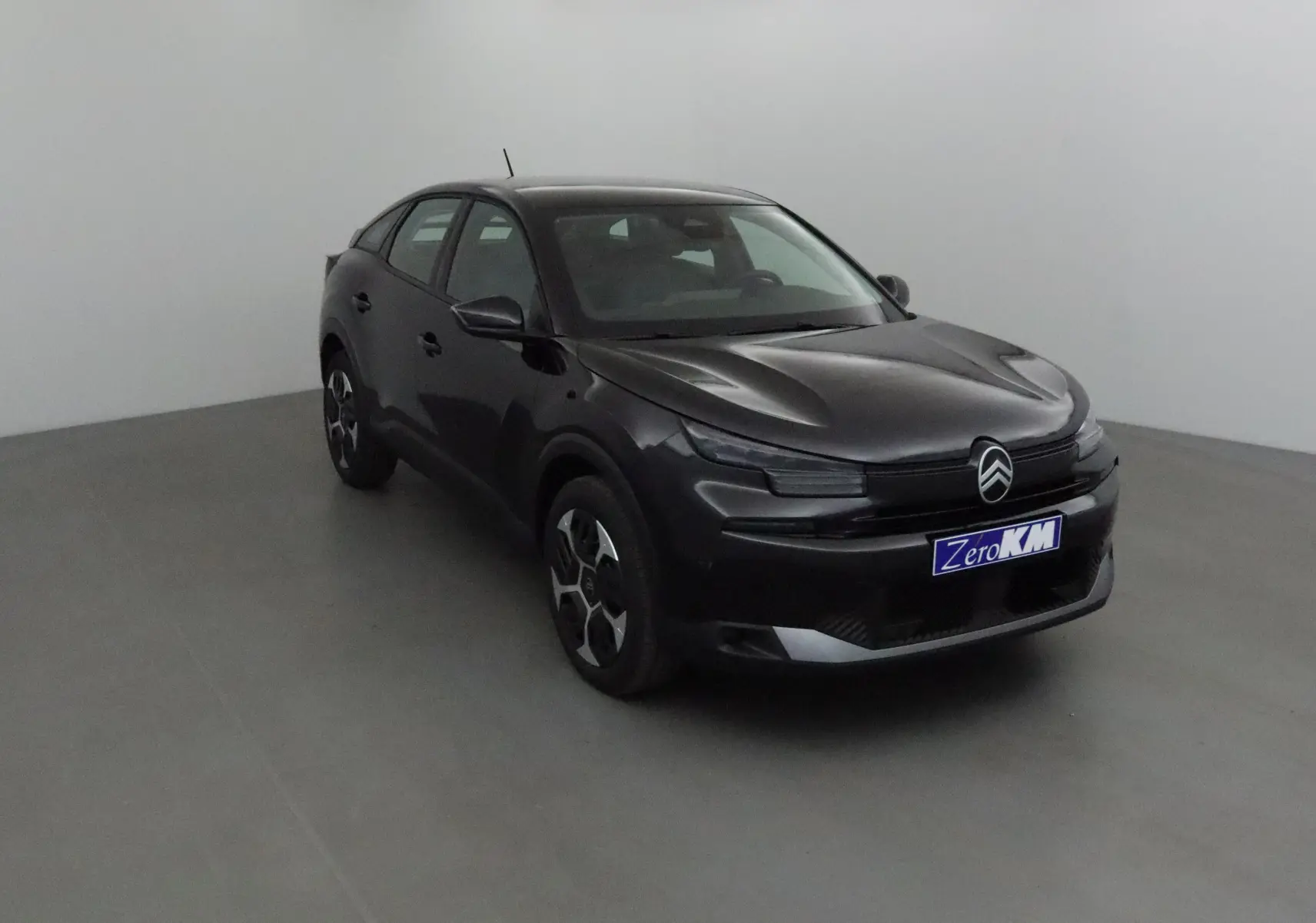 Citroën C4 1.2 Hybrid 145 noir vue 3/4 avant dans un studio, avec calandre noire et jantes stylisées.