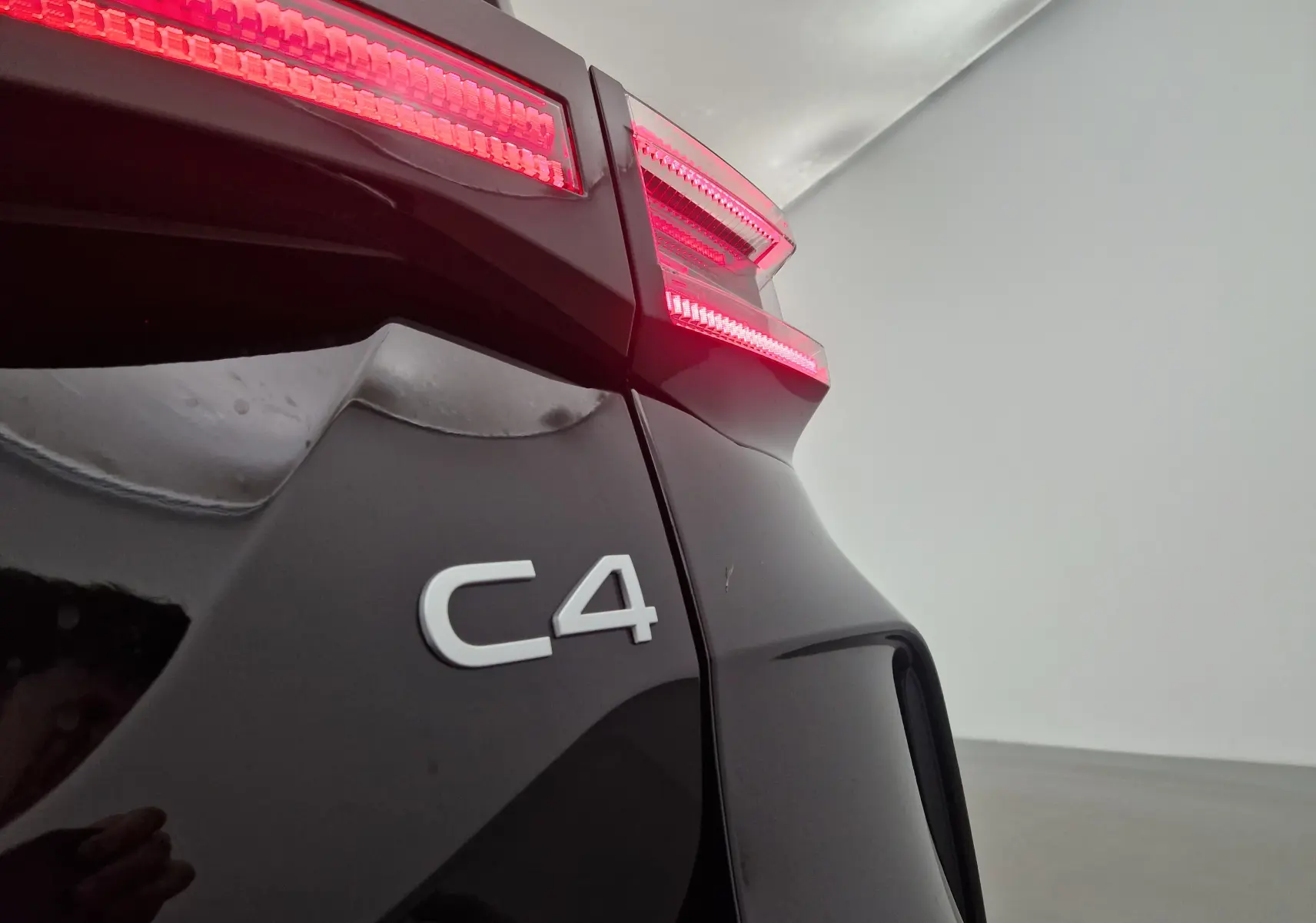 Gros plan sur le feu arrière droit rouge et l'inscription C4 du coffre noir d'une Citroën C4 2025.