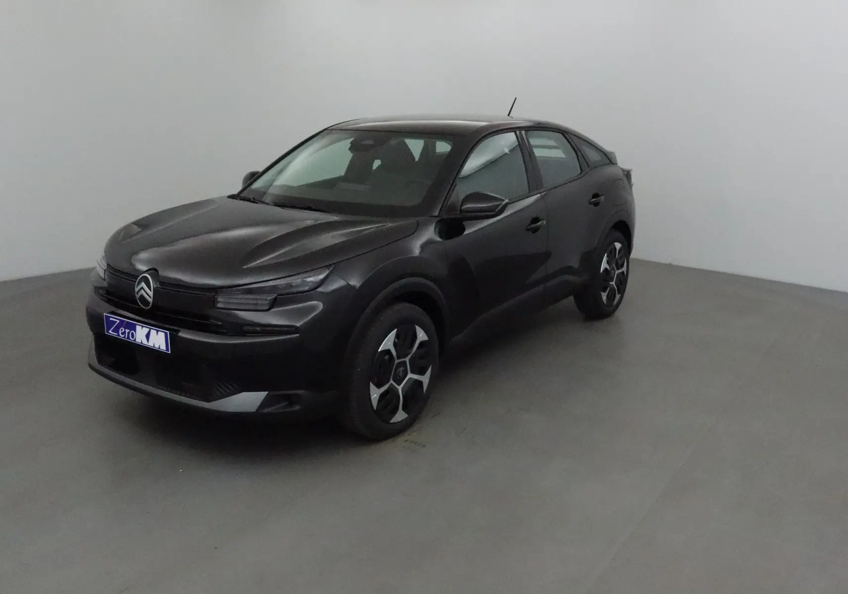 Citroën C4 1.2 Hybrid 145 noir vue 3/4 avant droit dans un studio avec jantes distinctives.