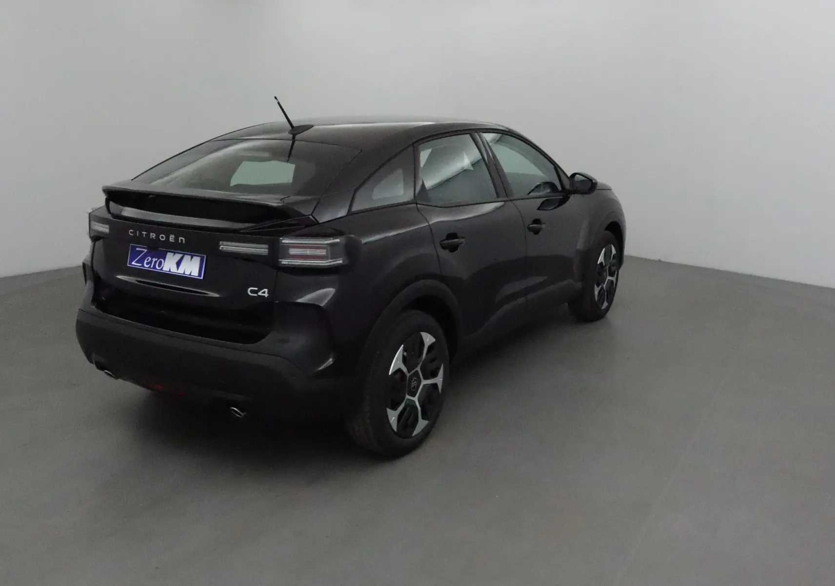 Vue 3/4 arrière droite d'une Citroën C4 noire 2025 avec toit incliné et jantes au design moderne.