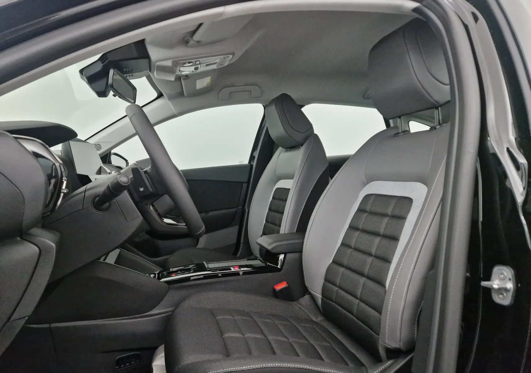 Intérieur avant droit d'une Citroën C4 noire 2025, sièges tissu noir et gris avec accoudoir central.