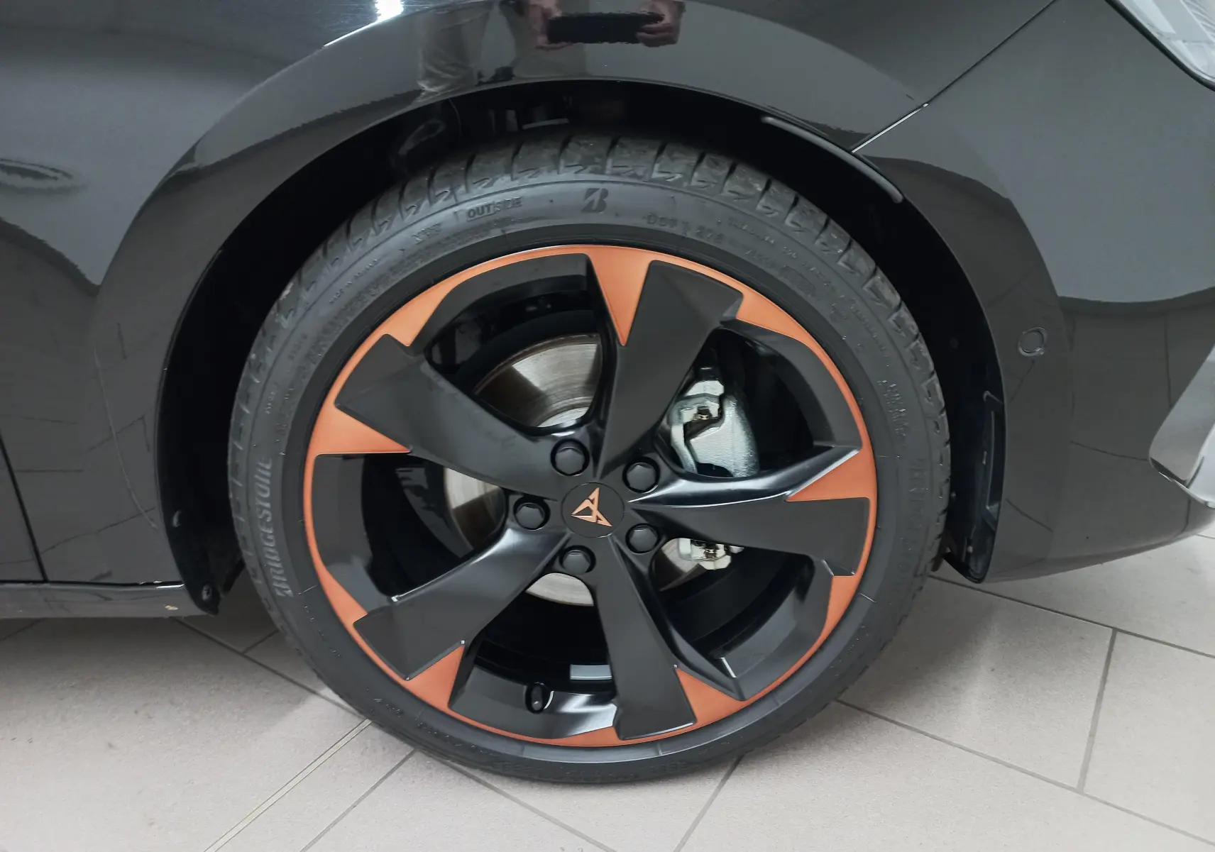 Gros plan sur la jante alliage 18'' cuivrée et noire du côté avant droit d'une CUPRA Leon Noir Minuit.