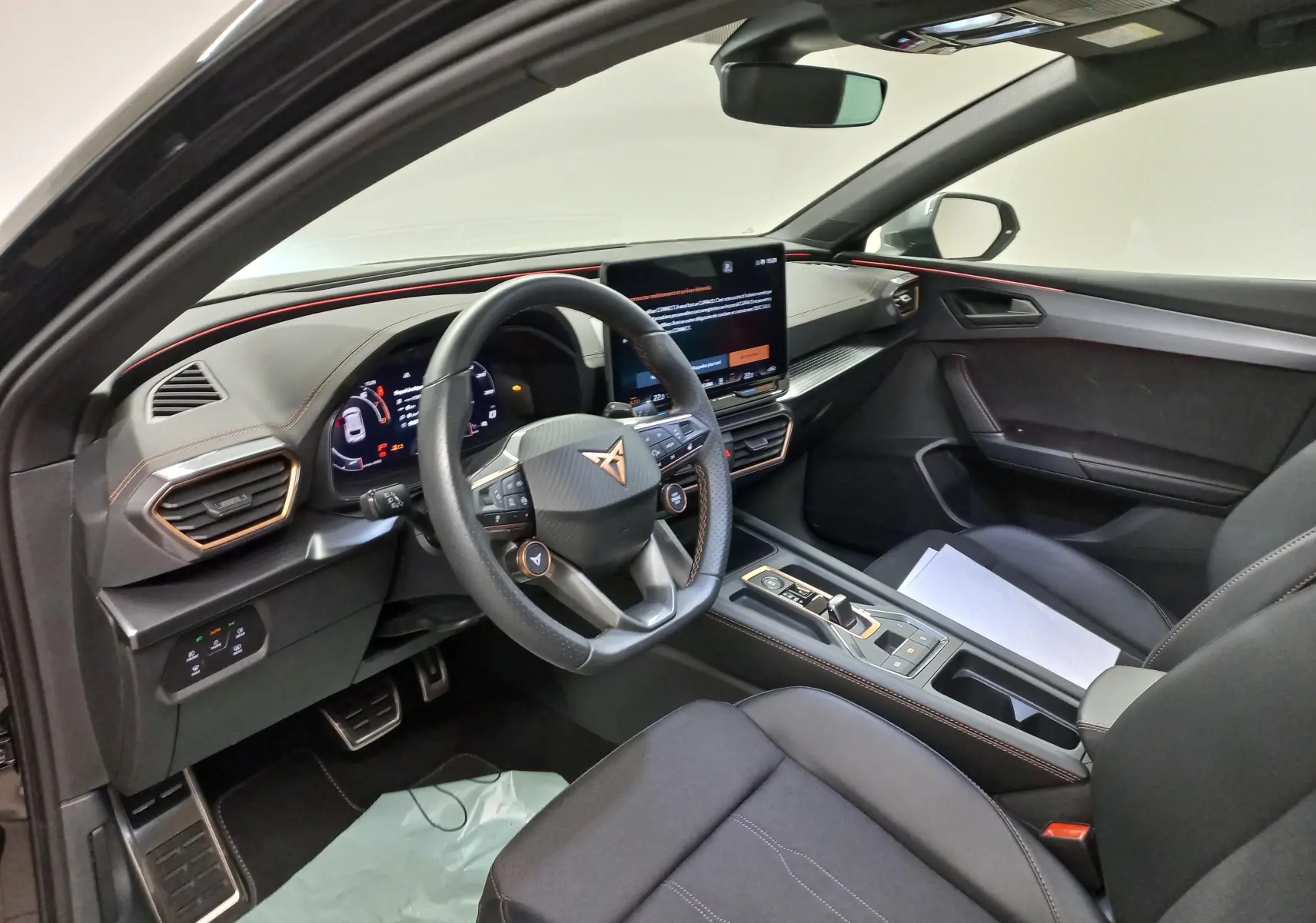 Intérieur côté conducteur de la CUPRA Leon 2025 noir Minuit, avec volant multifonction et écran central tactile.