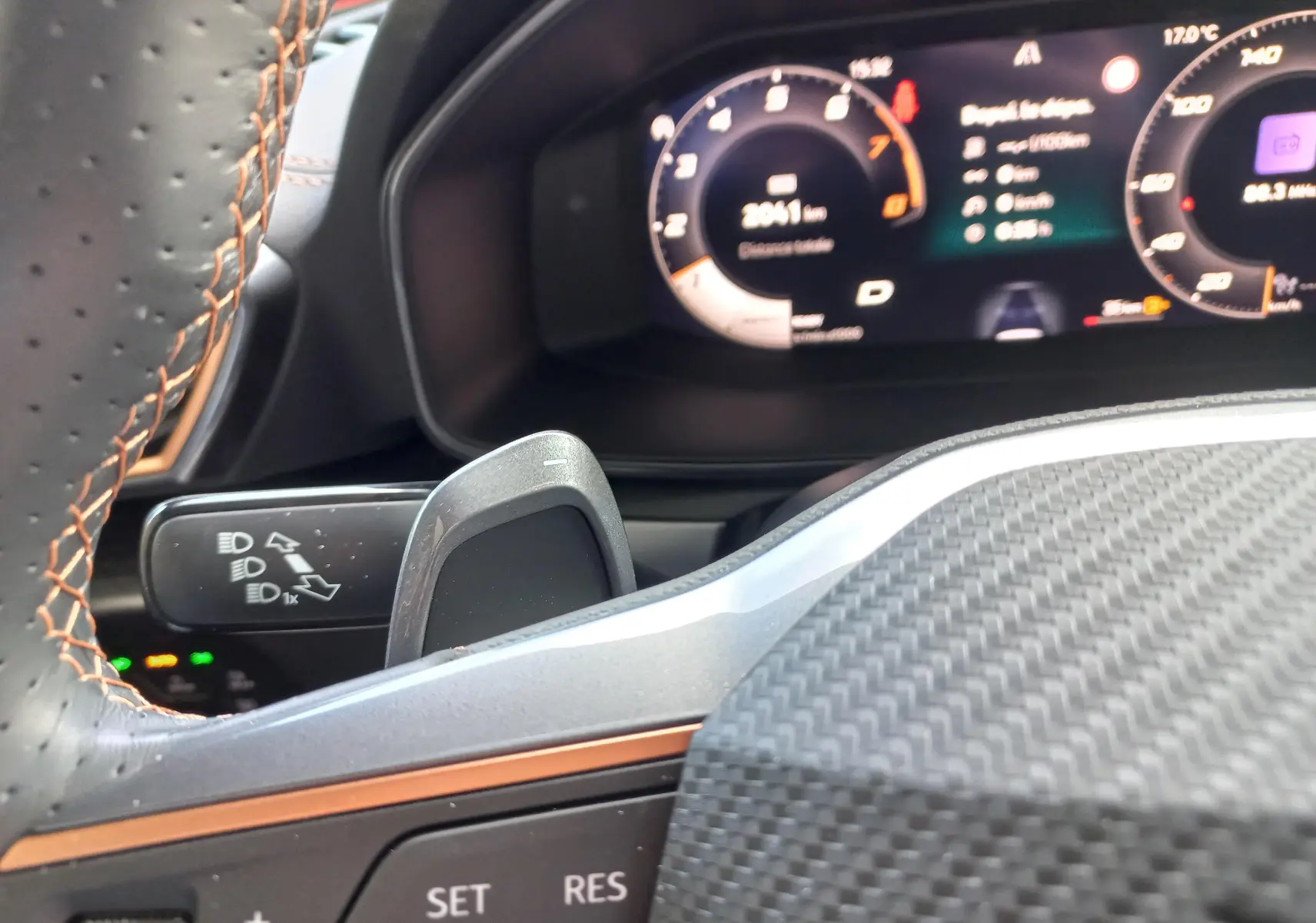 Gros plan sur le volant en cuir noir avec surpiqûres cuivrées et le tableau de bord numérique du CUPRA Leon 2025.