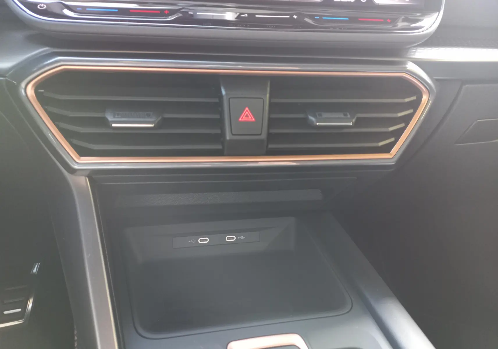 Détail de la console centrale noire avec bordure cuivrée et prises USB-C dans une CUPRA Leon 2025.