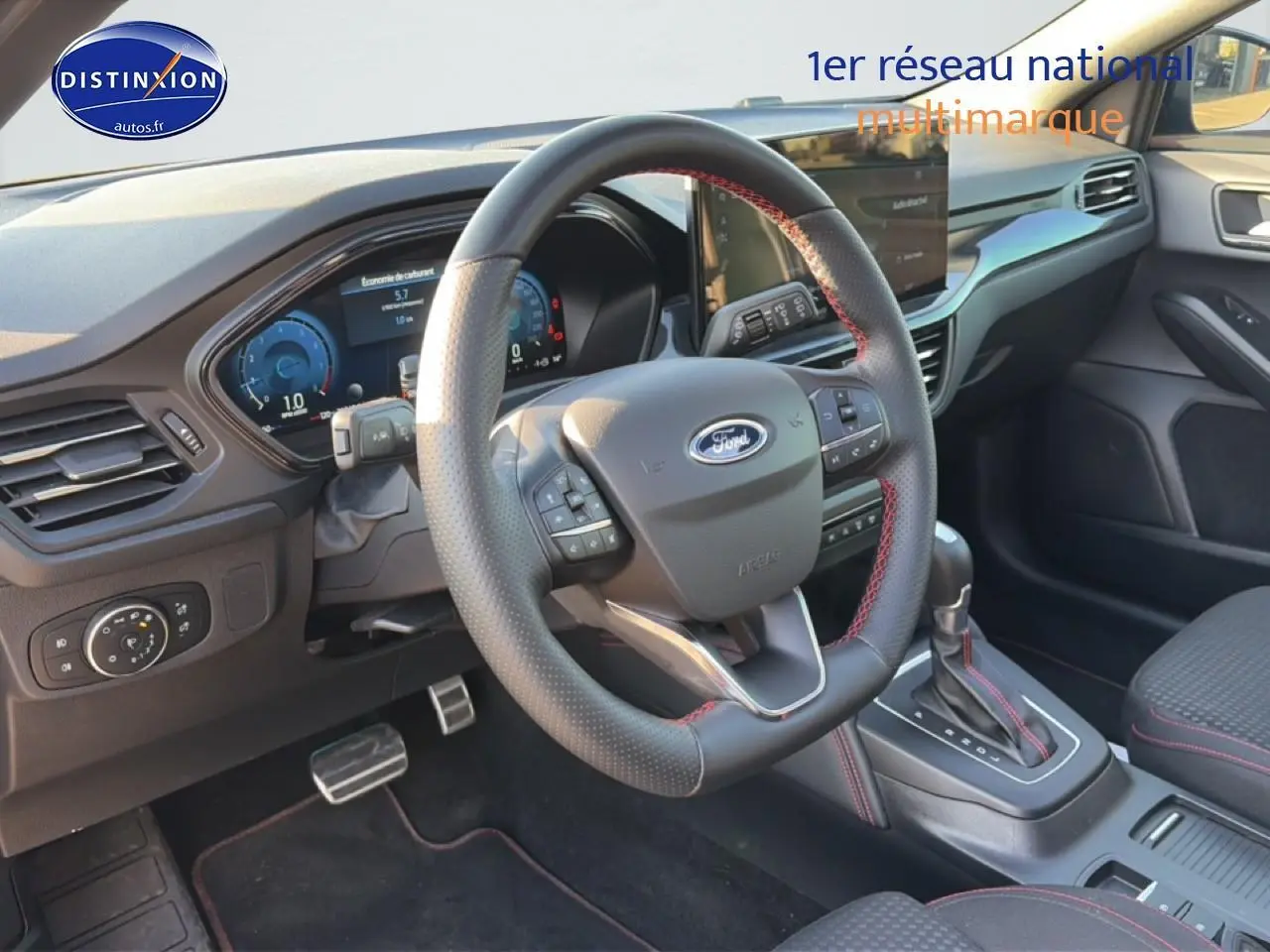 Intérieur avant droit de la Ford Focus noire 2024, volant cuir sport avec surpiqûres rouges et console centrale automatique.