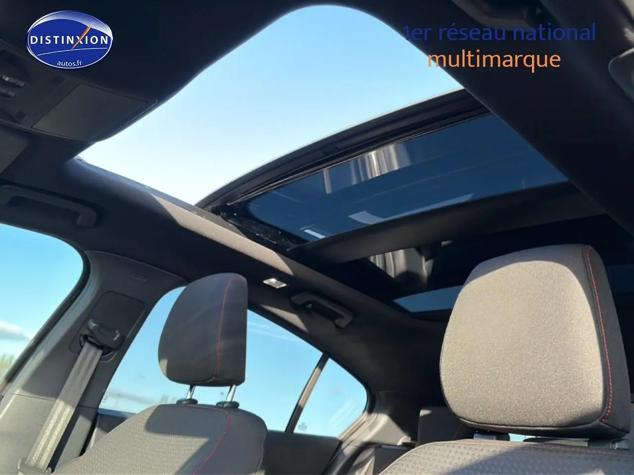 Vue intérieure de la Ford Focus 2024 noire, mettant en valeur les sièges avant et le toit ouvrant panoramique.