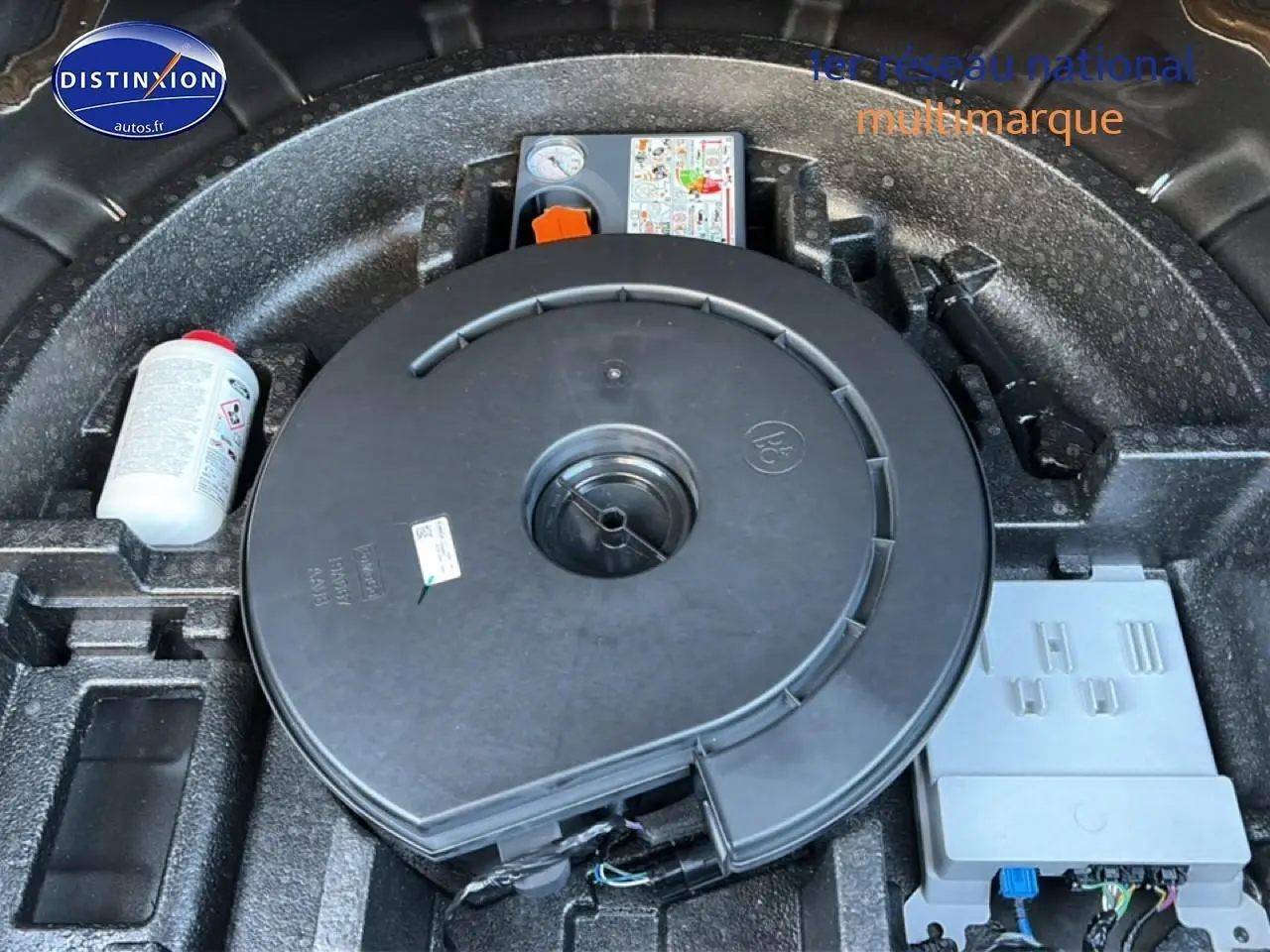 Vue rapprochée du compartiment de roue de secours d'une Ford Focus noire 2024, montrant le kit de réparation et les outils intégrés.