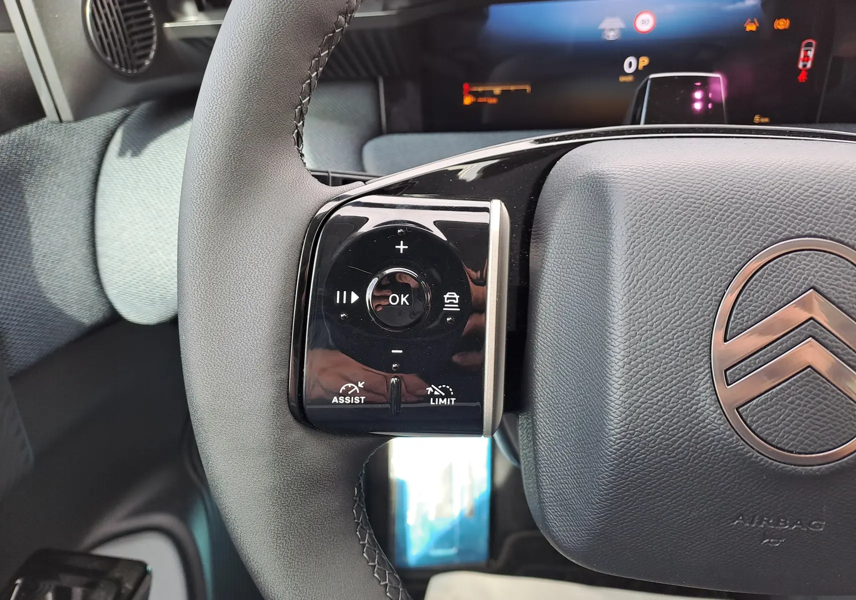 Gros plan sur le volant gris noir du Citroën C5 Aircross 2026, avec commandes tactiles et logo central visible.