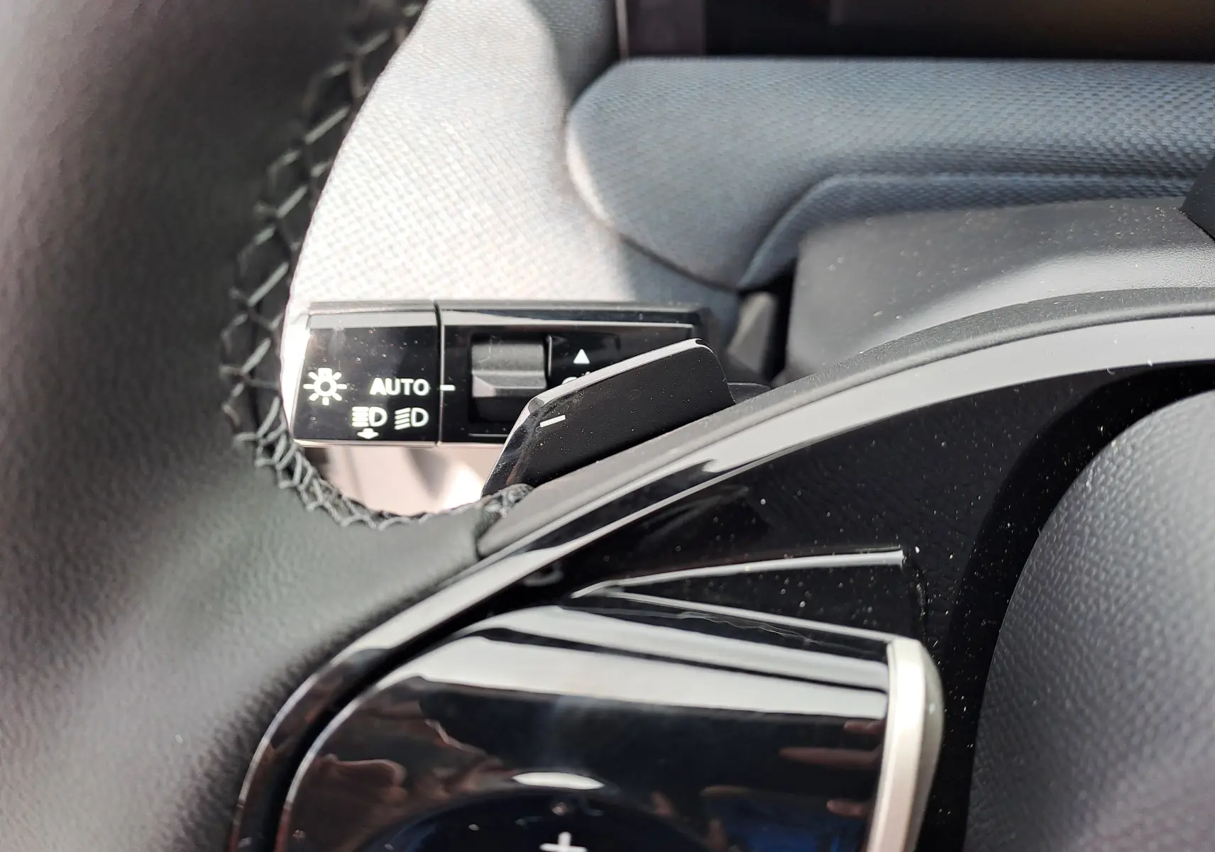 Gros plan sur la commande d’éclairage et la palette de changement de vitesse noire dans l’habitacle gris du Citroën C5 Aircross.