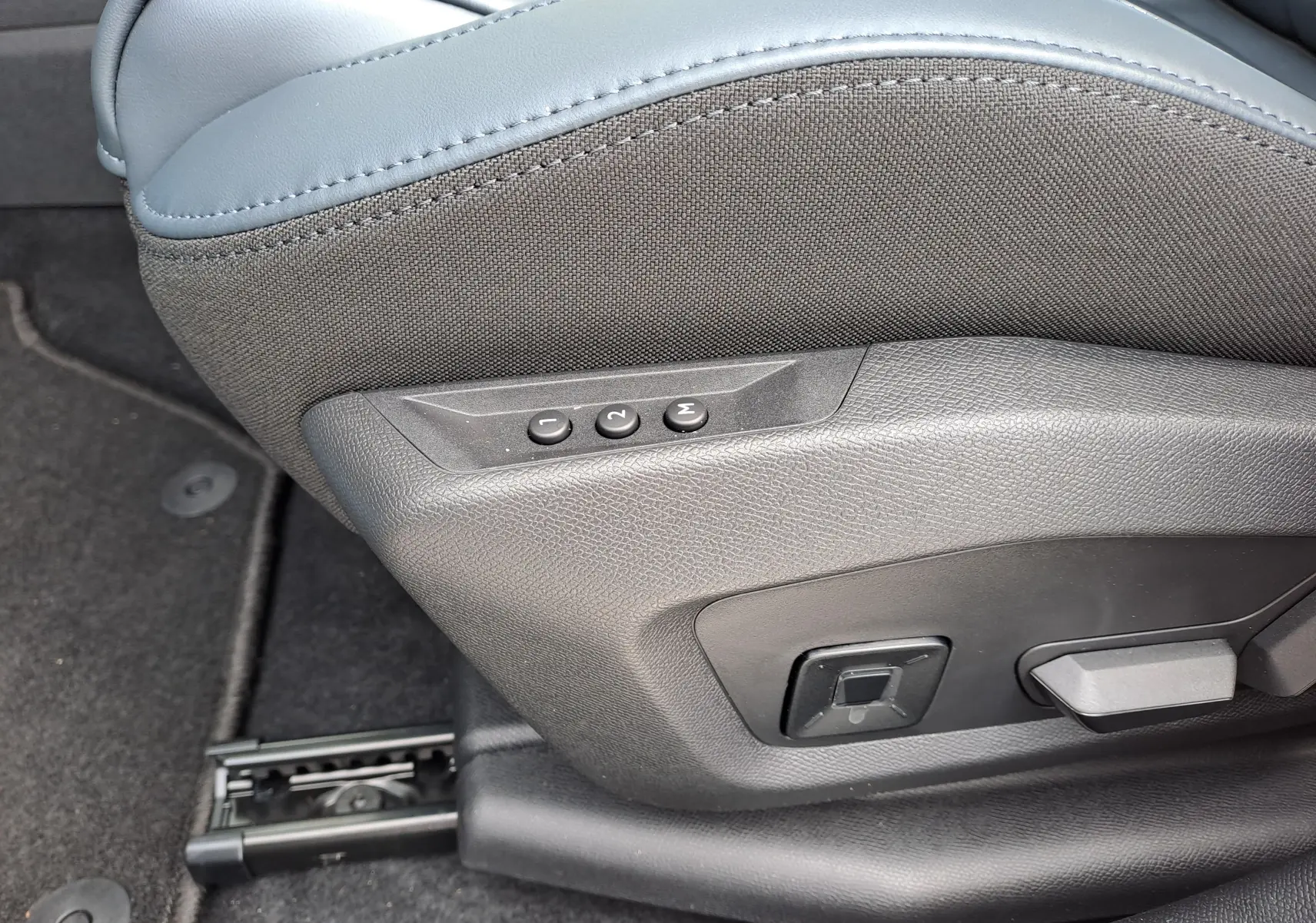 Gros plan sur la commande de réglage électrique du siège avant en tissu gris et cuir bleu dans un Citroën C5 Aircross hybride 2026.