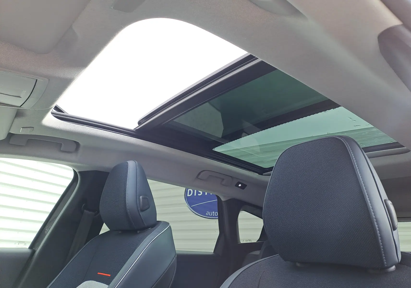 Vue intérieure du toit ouvrant panoramique et des sièges avant en tissu gris foncé du Citroën C5 Aircross hybride 2026.