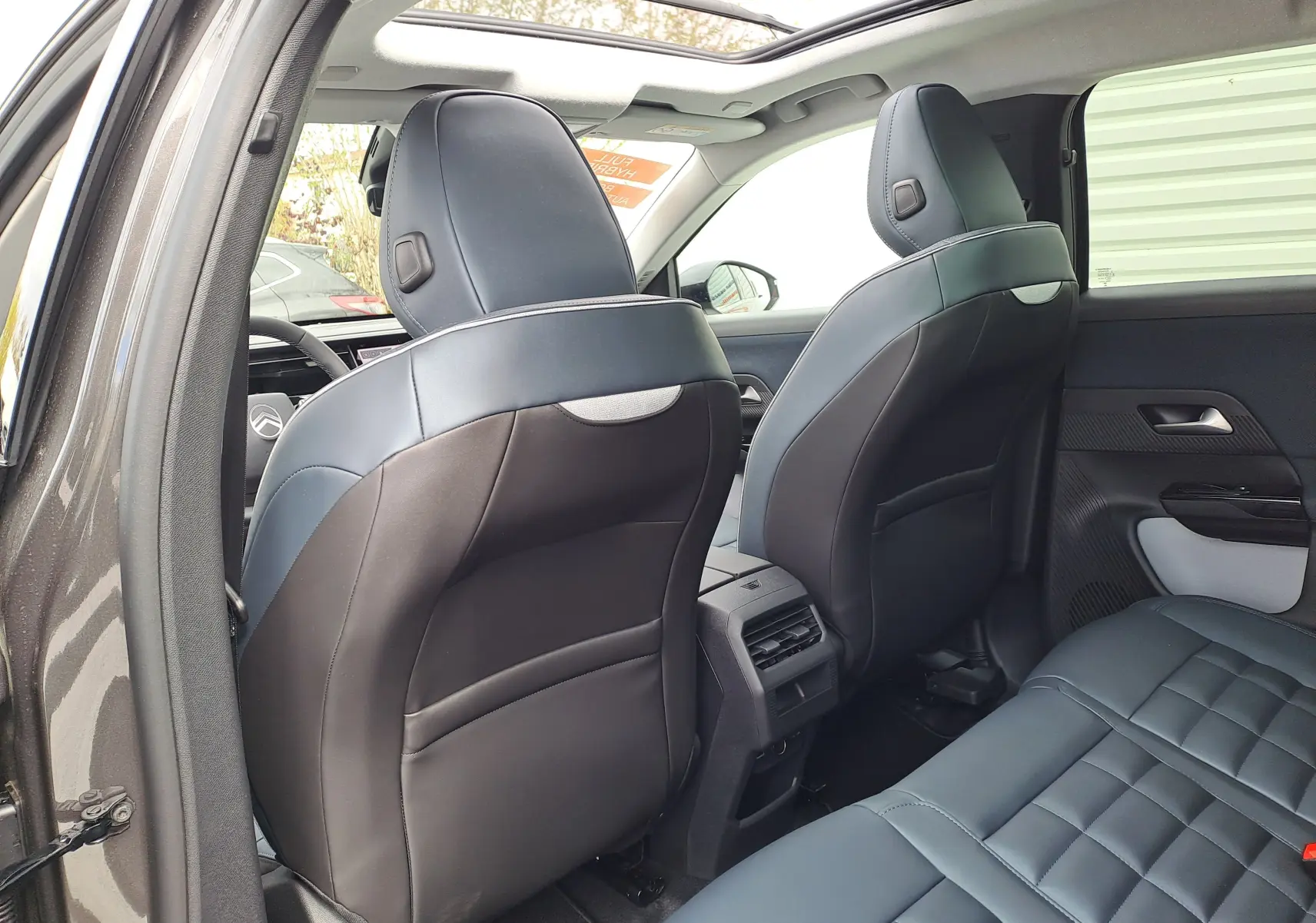 Vue arrière intérieure du Citroën C5 Aircross gris platinium, montrant les sièges avant en cuir noir et l'espace arrière.