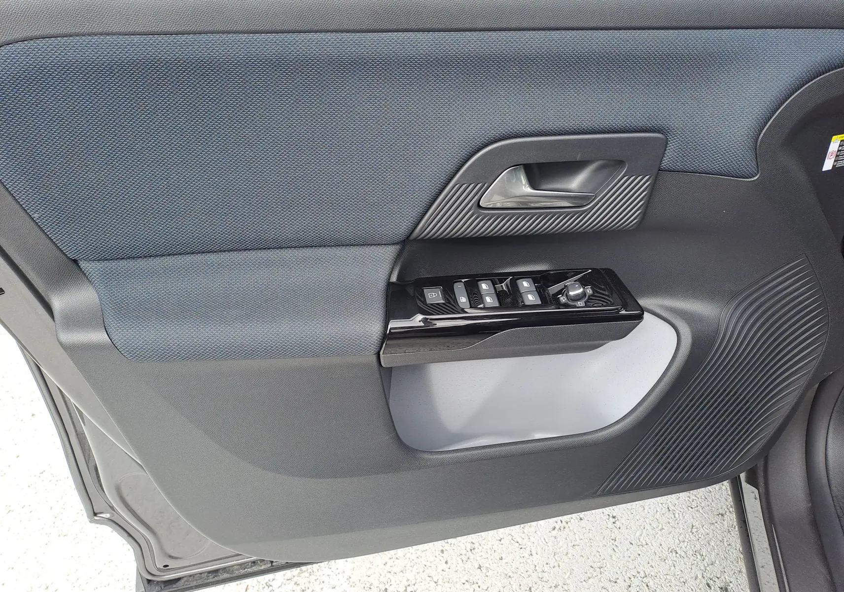 Gros plan sur la porte intérieure côté conducteur du Citroën C5 Aircross gris platinium, avec commandes de vitres et poignée noire.