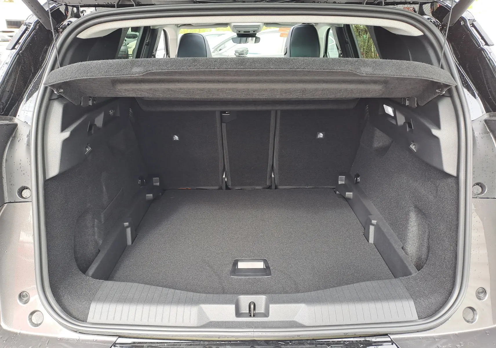 Coffre ouvert vu de l'arrière d'un Citroën C5 Aircross gris platinium avec intérieur noir et banquette arrière visible.