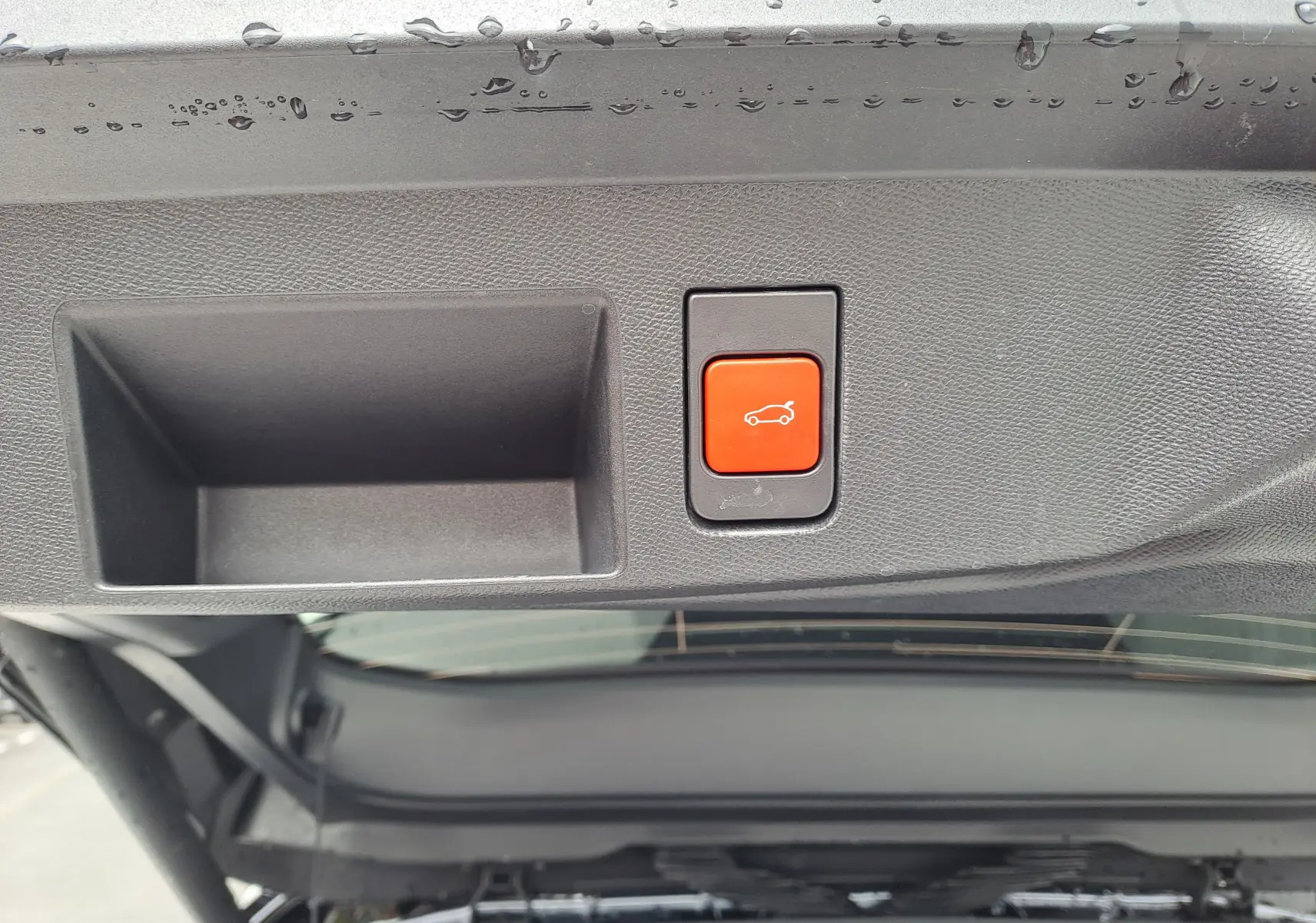 Bouton rouge d'ouverture électrique du hayon sur le coffre arrière d'un Citroën C5 Aircross gris platinium.