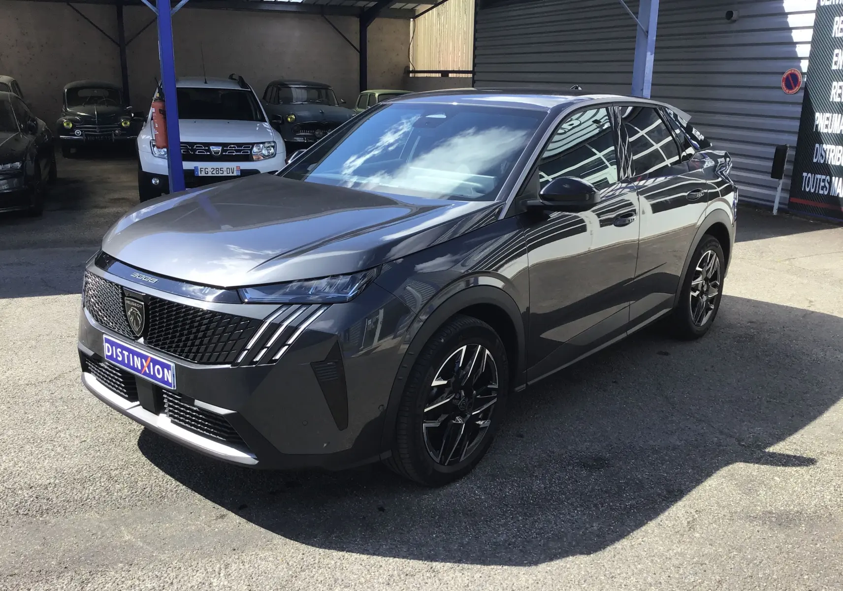 Vue 3/4 avant droite du Peugeot 3008 gris titane 2026 avec calandre distinctive et jantes noires brillantes.