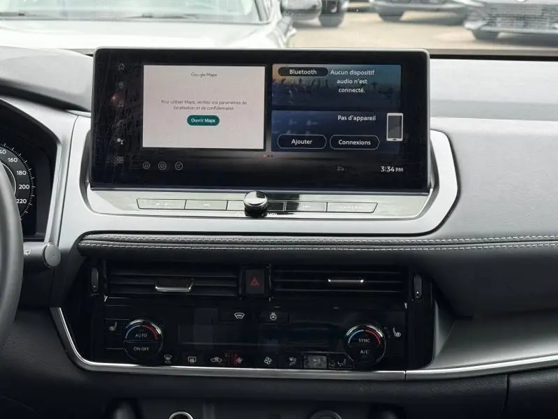 Vue intérieure du tableau de bord du Nissan Qashqai 2025 avec écran tactile central affichant Google Maps et Bluetooth.