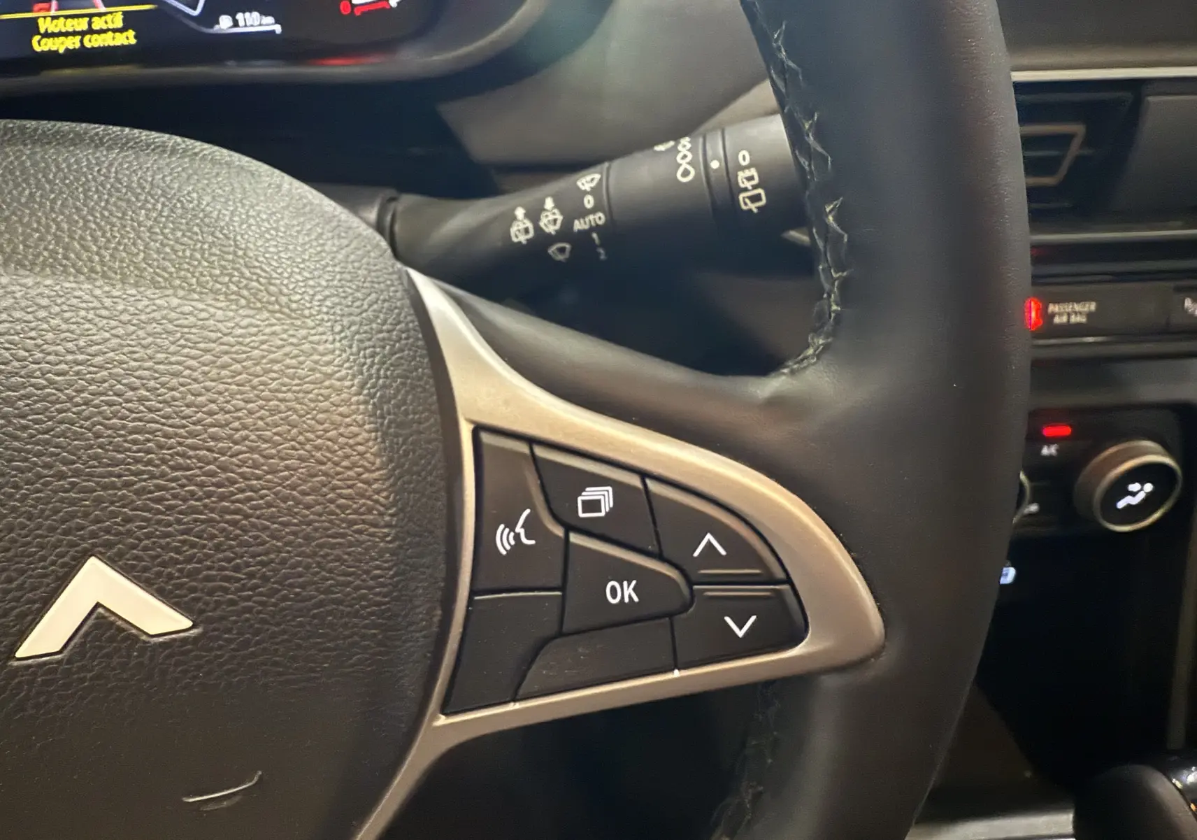 Gros plan sur le côté droit du volant en cuir noir du Dacia Jogger Hybrid 140 Extreme avec commandes intégrées.