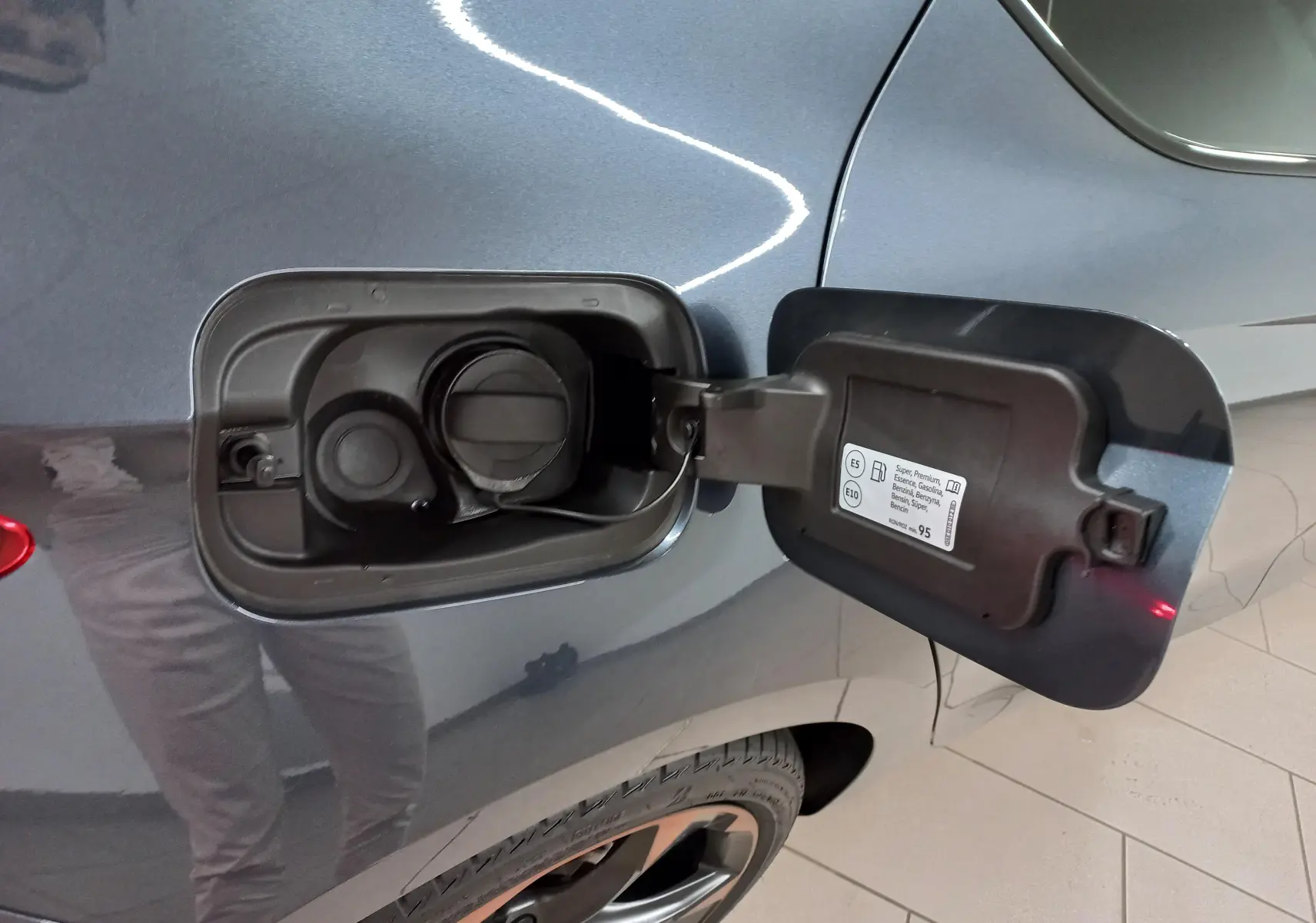 Bouchon de réservoir ouvert côté gauche sur CUPRA Leon gris magnétique avec jante alliage 18 pouces cuivrée visible.