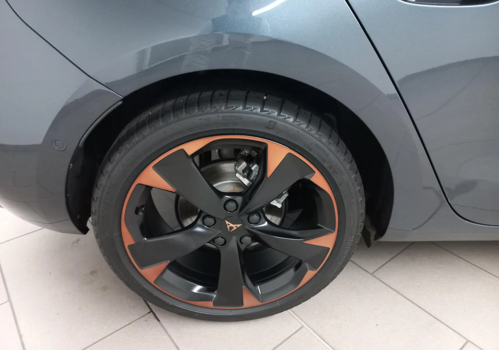 Gros plan sur la jante cuivrée et noire d'une CUPRA Leon gris magnétique, côté arrière droit du véhicule.