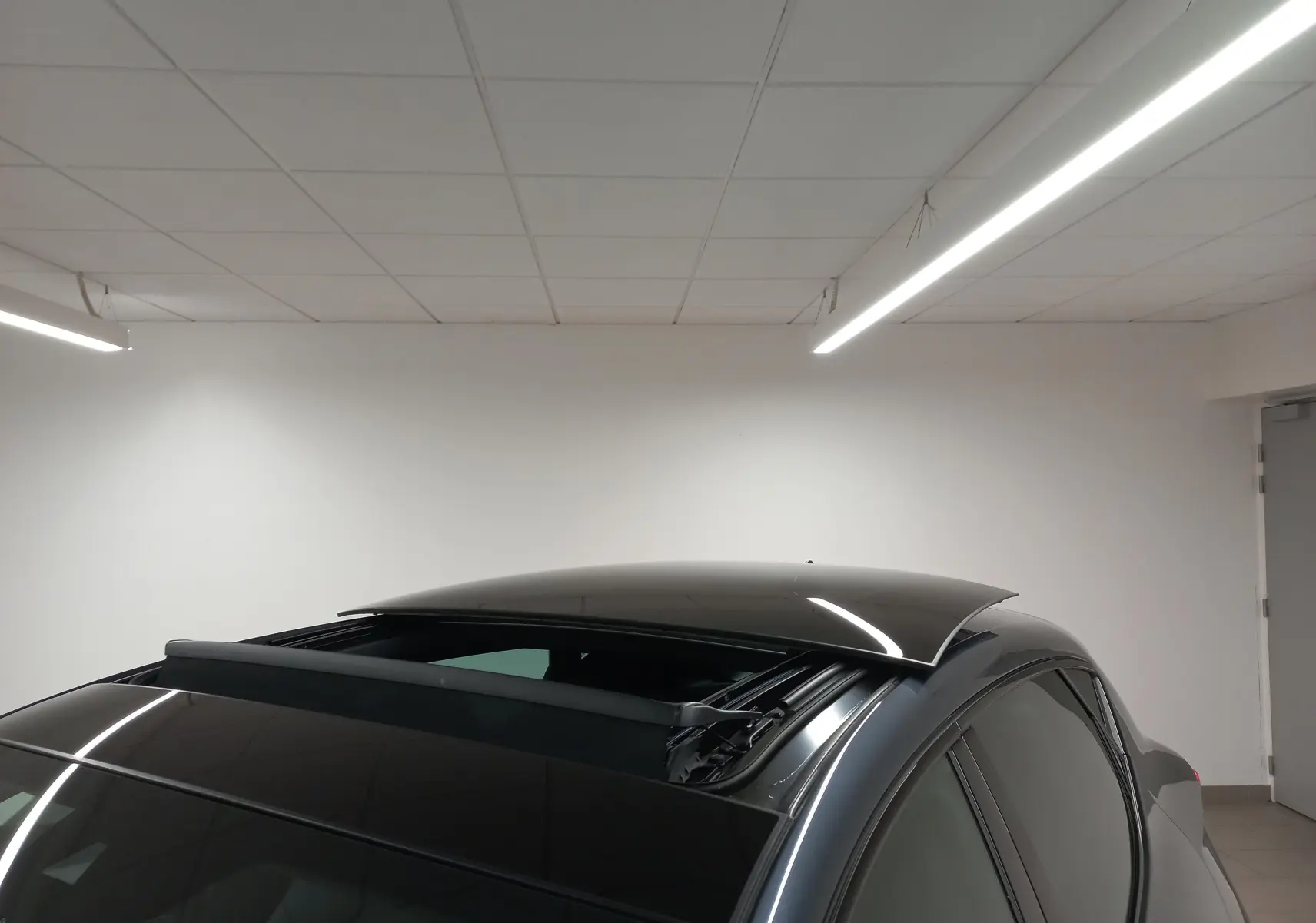 Toit ouvrant panoramique ouvert sur le côté gauche d'une CUPRA Leon 2025 gris magnétique en intérieur.